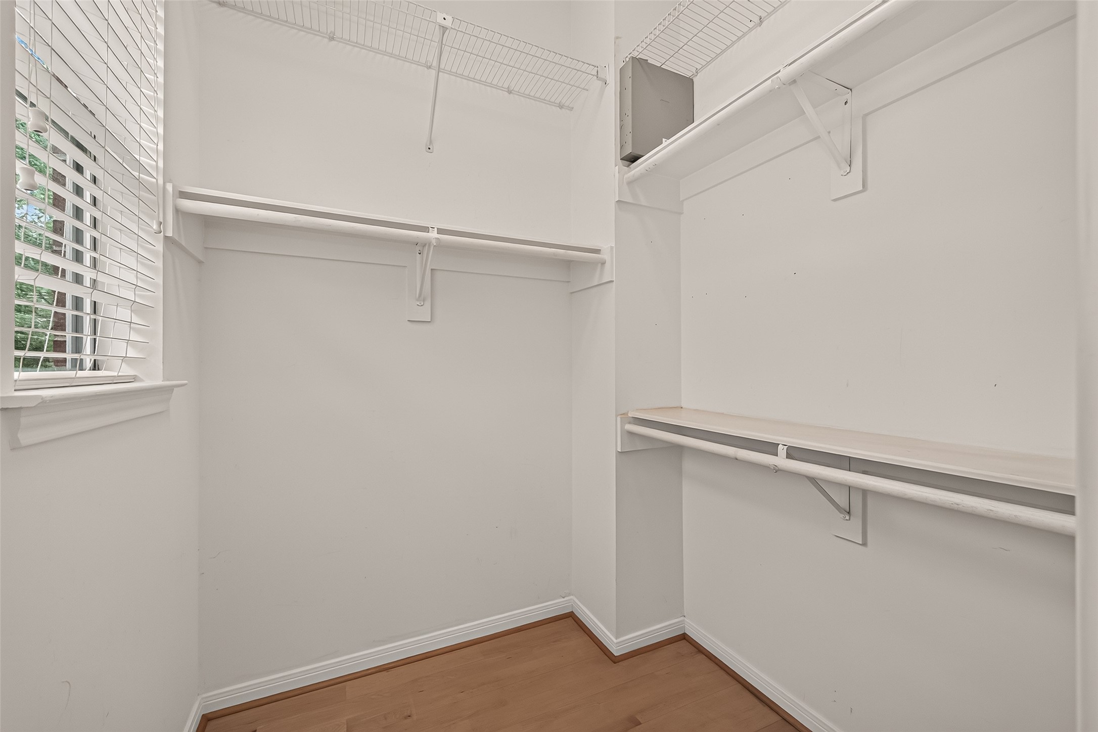 One of two closets in the primary bedroom, featuring a window that brings in natural light and adds a unique touch to the space.