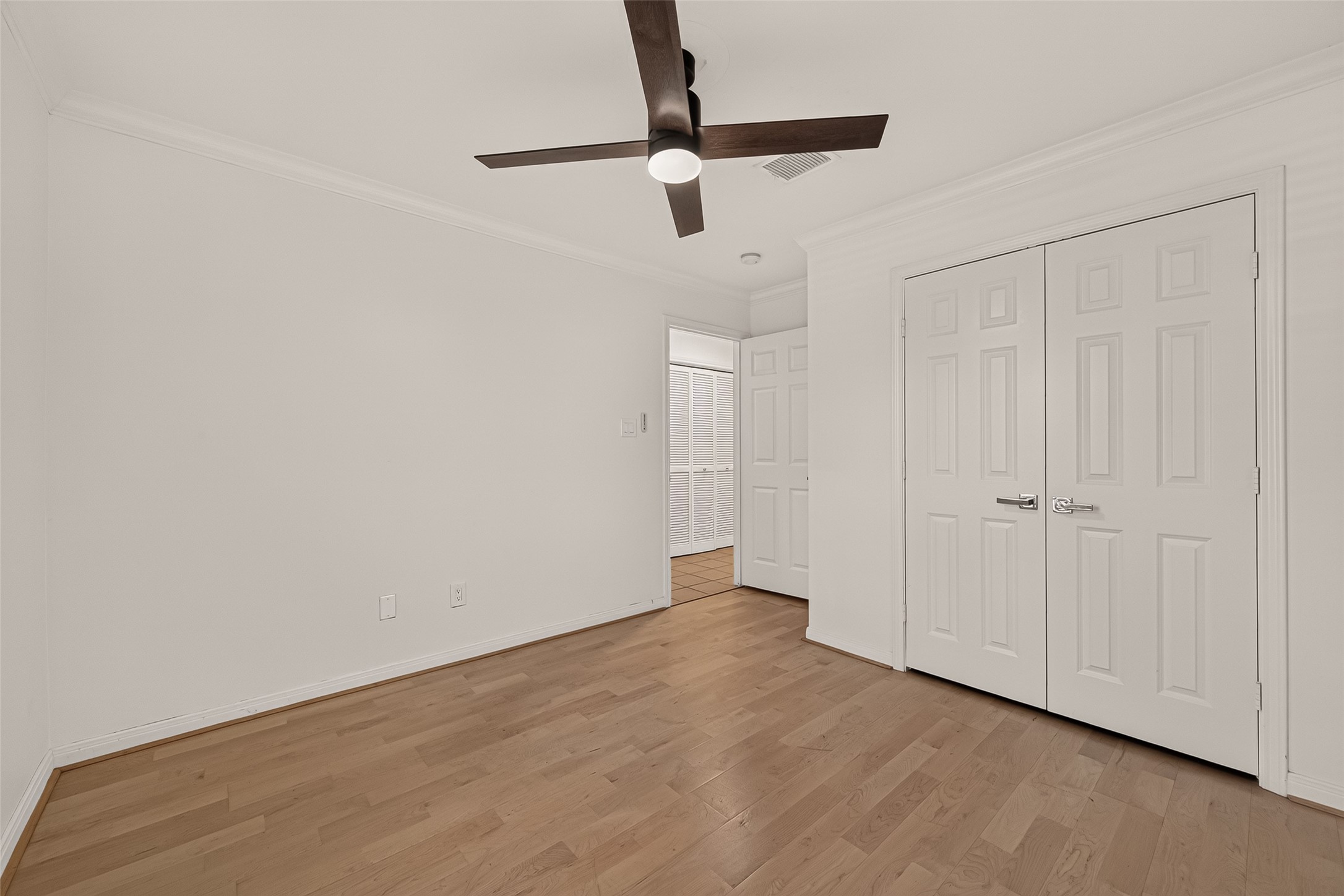 Another view of 1st floor secondary bedroom, showing the closet the double closet doors and entry to the hallway.