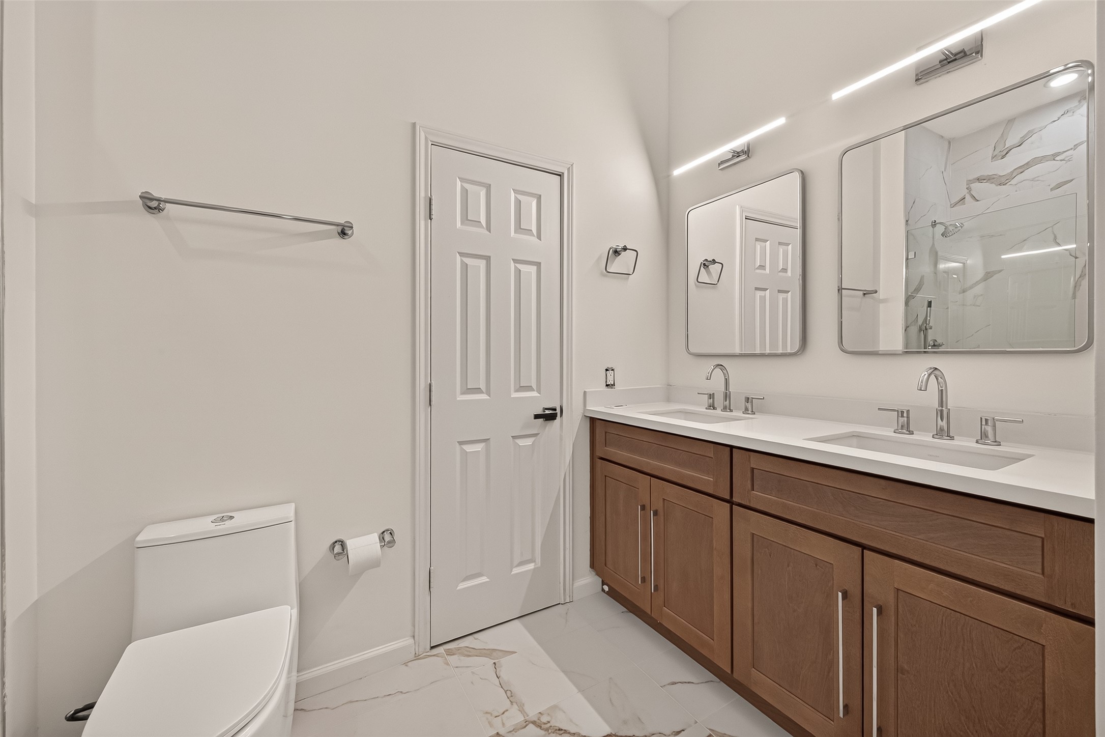 Updated primary bathroom featuring a double-sink vanity, lighted mirrors, and modern light fixtures for a clean, contemporary look.
