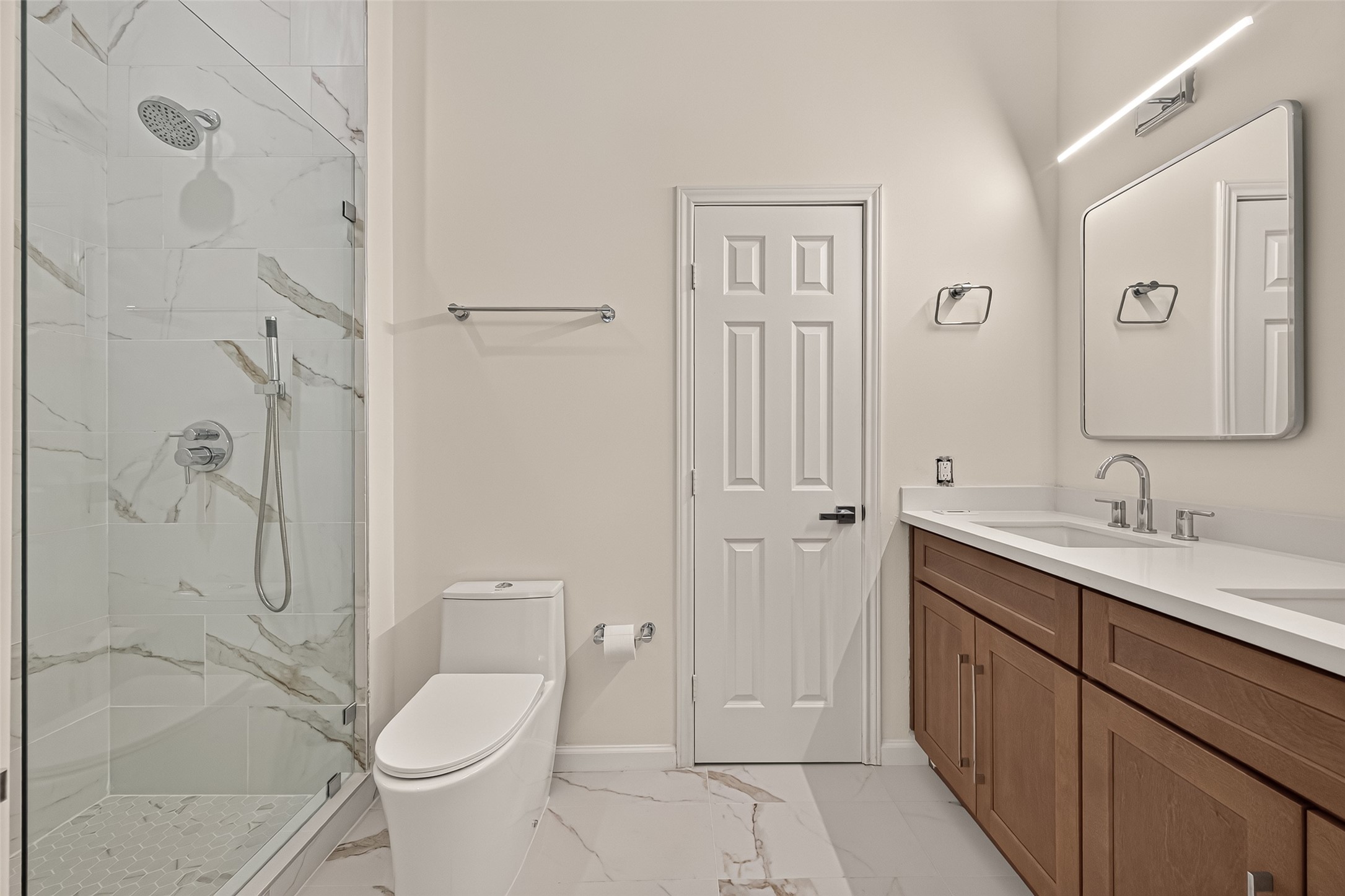 The beautifully updated primary bathroom features a double-sink vanity, separate commode area, and a large walk-in shower.