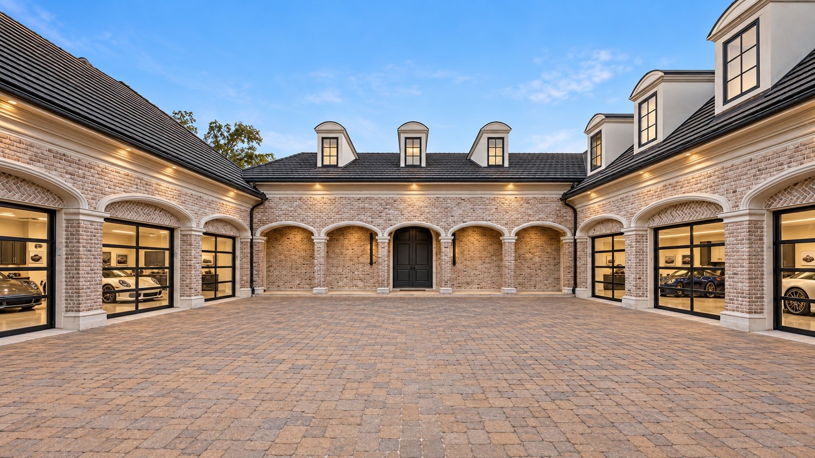 An extraordinary motor court is framed by coordinated architectural elevations and multiple garage bays, providing a grand arrival setting and substantial space for vehicle parking and circulation.