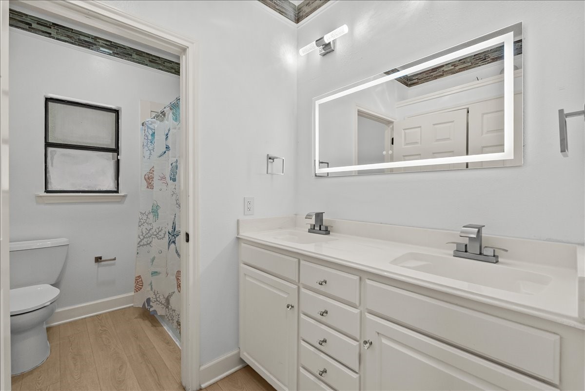 Thoughtfully designed guest bath featuring a dedicated vanity area with a modern illuminated mirror, while a separate enclosed space houses the tub/shower combination and toilet for added privacy and convenience.