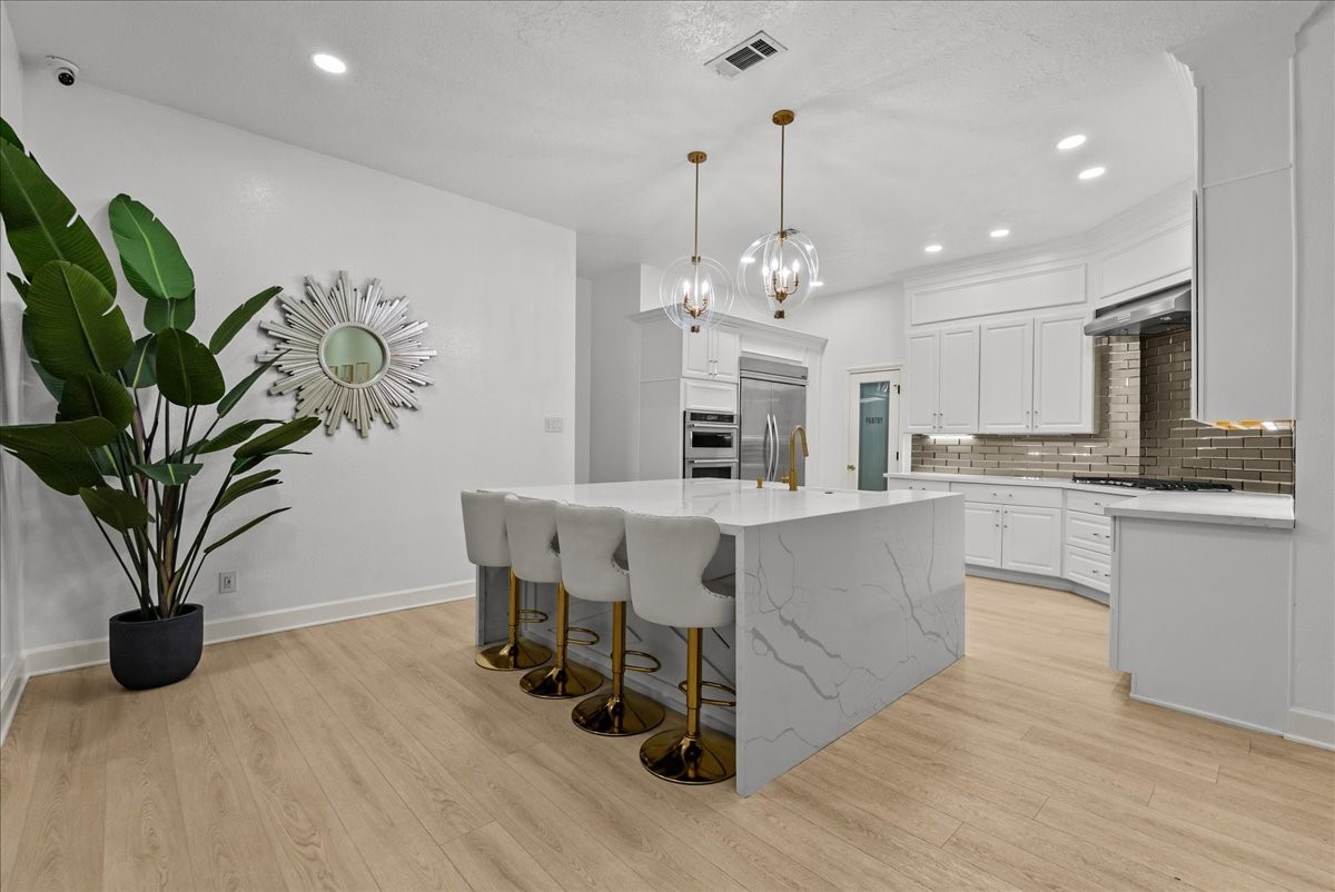 A stunning waterfall island takes center stage, offering generous seating, a farmhouse sink, and the perfect place for morning coffee, casual meals, or entertaining family and friends.