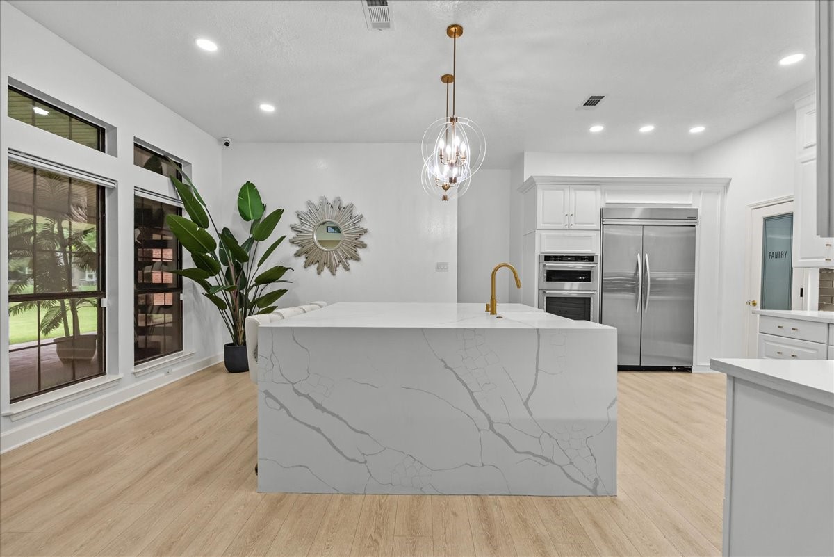 Three impressive floor-to-ceiling windows flood the kitchen with natural light, creating a bright, airy space while offering picturesque views of the surrounding property.