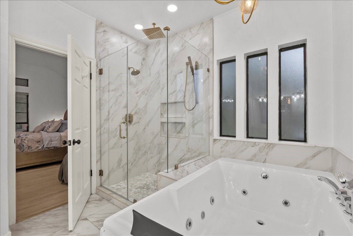 Step into your own private spa retreat featuring a stunning two-person jetted soaking tub with hydrotherapy jets, LED chroma lighting, waterfall faucet, and dual headrests, along with a custom Delta shower system offering dual shower heads, rainfall shower, and multi-function controls.