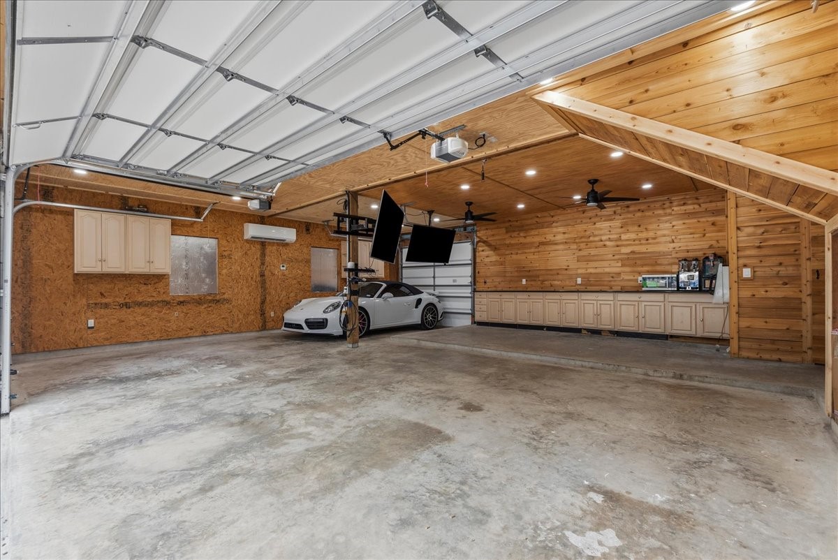 More than just a garage, this space was designed for enjoyment and functionality with custom-style beadboard and shiplap details, abundant cabinetry, granite countertops, a built-in entertainment area with two TVs, and an EV charging station. Whether used as a workshop, game space, or gathering area, this garage offers endless possibilities. More than just a garage, this space was designed for enjoyment and functionality with custom-style beadboard and shiplap details, abundant cabinetry, granite countertops, a built-in entertainment area with two TVs, and an EV charging station. Whether used as a workshop, game space, or gathering area, this garage offers endless possibilities.