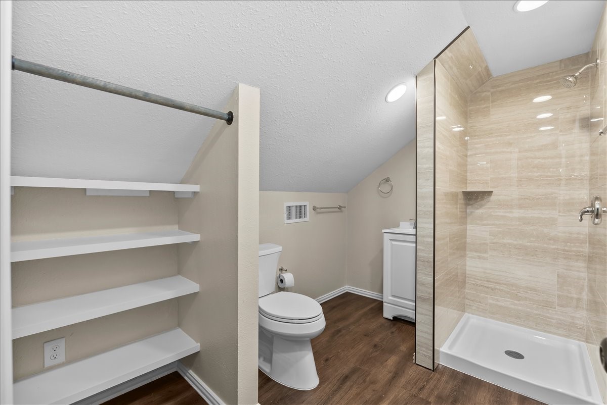 The second level of the garage features a newly renovated full bathroom showcasing a sleek walk-in shower with floor-to-ceiling tile, creating a comfortable and stylish space for guests, hobbies, or flexible living needs.