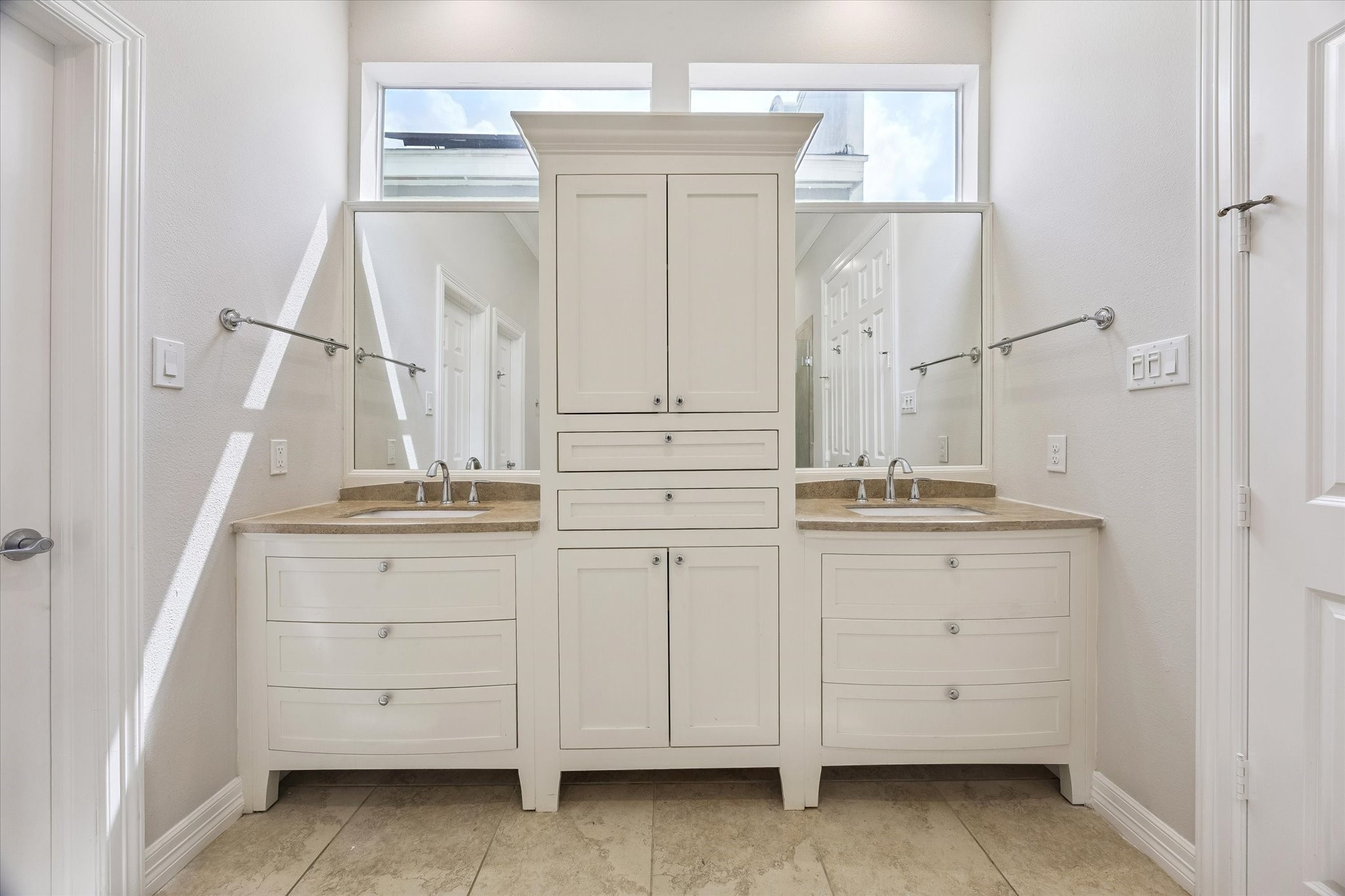 Elegant dual vanities with custom cabinetry around them. Note also the extra window above to let in natural light!