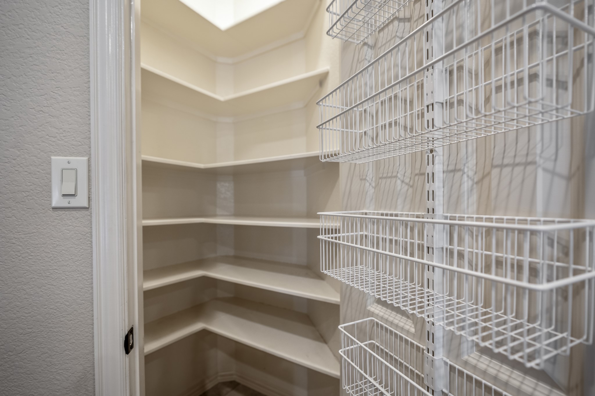 The pantry adds easy-to-reach storage with wraparound shelving and door-mounted racks for smaller items. Positioned right beside the working side of the kitchen, it keeps ingredients, serving pieces, and overflow neatly tucked away while staying close to the island, appliances, and main prep areas.