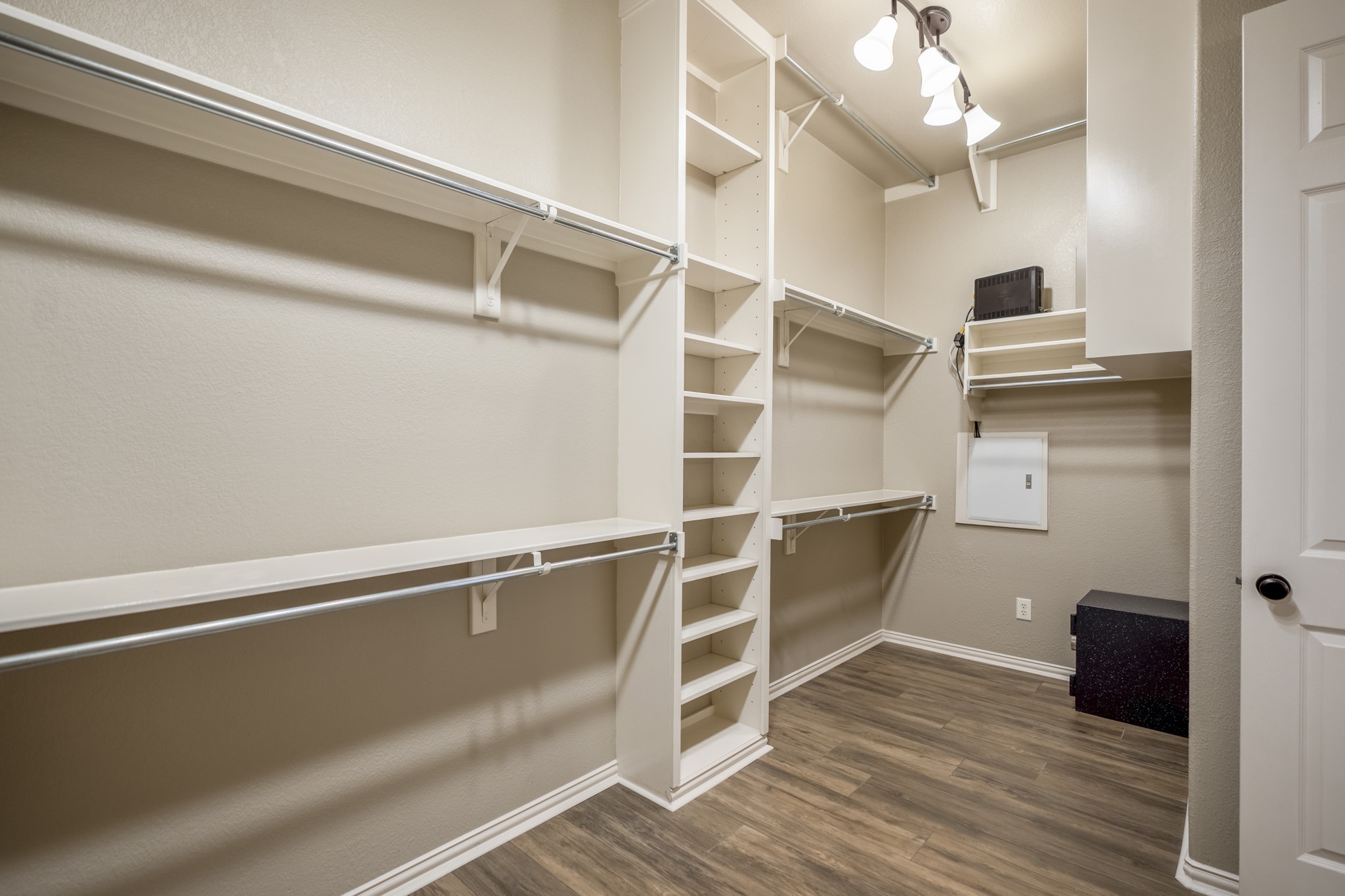 Continuing from the remodeled primary bath, the walk-in closet adds a well-planned extension of the suite with wraparound shelving, hanging space, and wide-plank wood-look tile carried through from the bedroom and bath. Its direct connection to the bath keeps the primary retreat feeling seamless, with storage placed right where buyers would expect it.