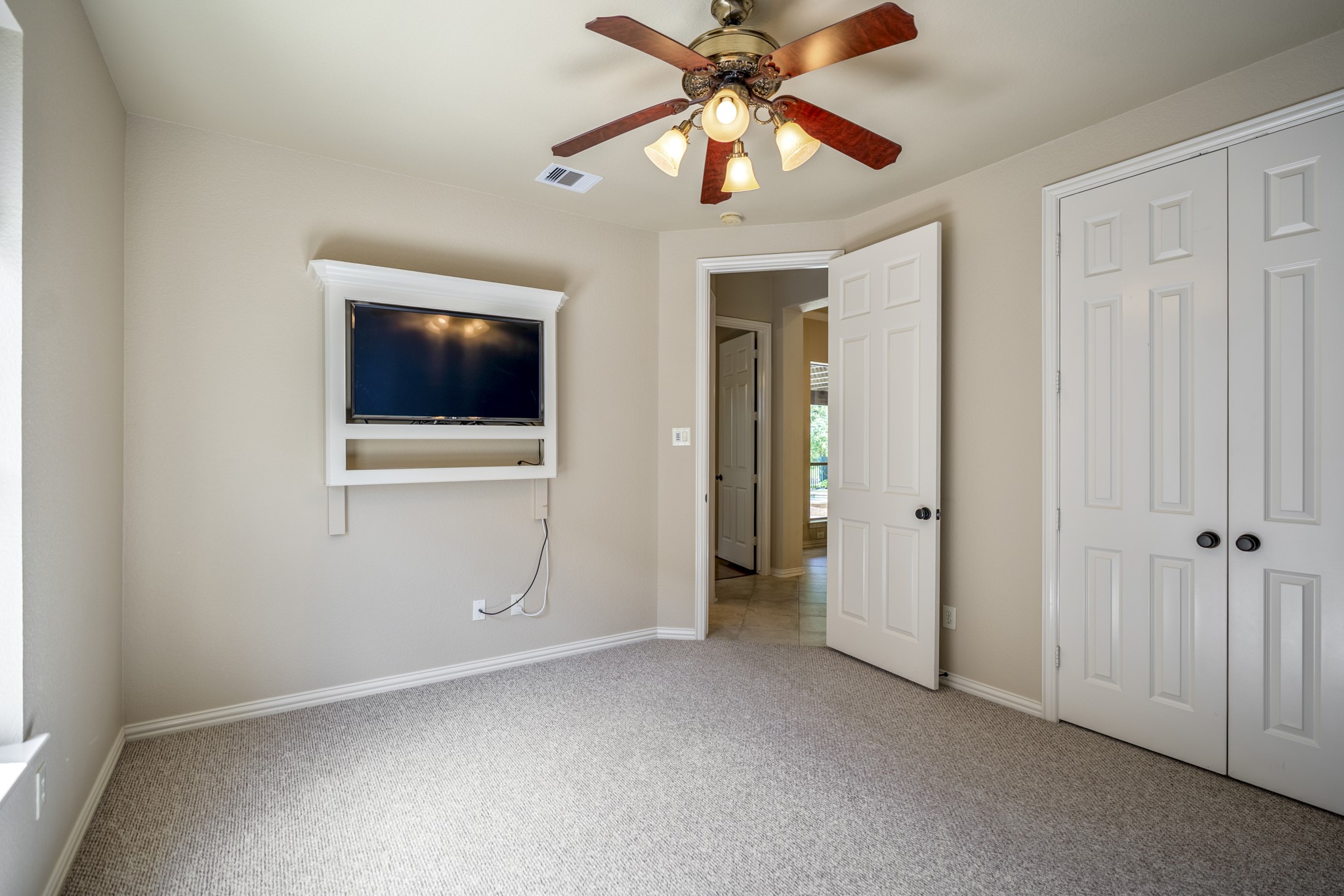 The fourth bedroom shows the closet doors along the right wall and the doorway leading back toward the nearby hall. From here, the walkthrough transitions toward the stairs, moving from the downstairs bedroom spaces up to the game room and media room above.