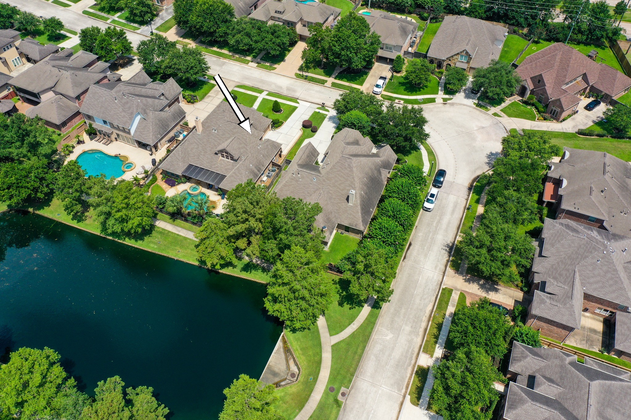 From above, the homes water-front setting comes into focus with the walking path, water, neighboring outdoor spaces, and pool/spa all visible. Behind the home, the covered outdoor living area and backyard overlook the water-view backdrop, creating an easy connection to the lake-centered lifestyle of Lakes of Cypress Forest.