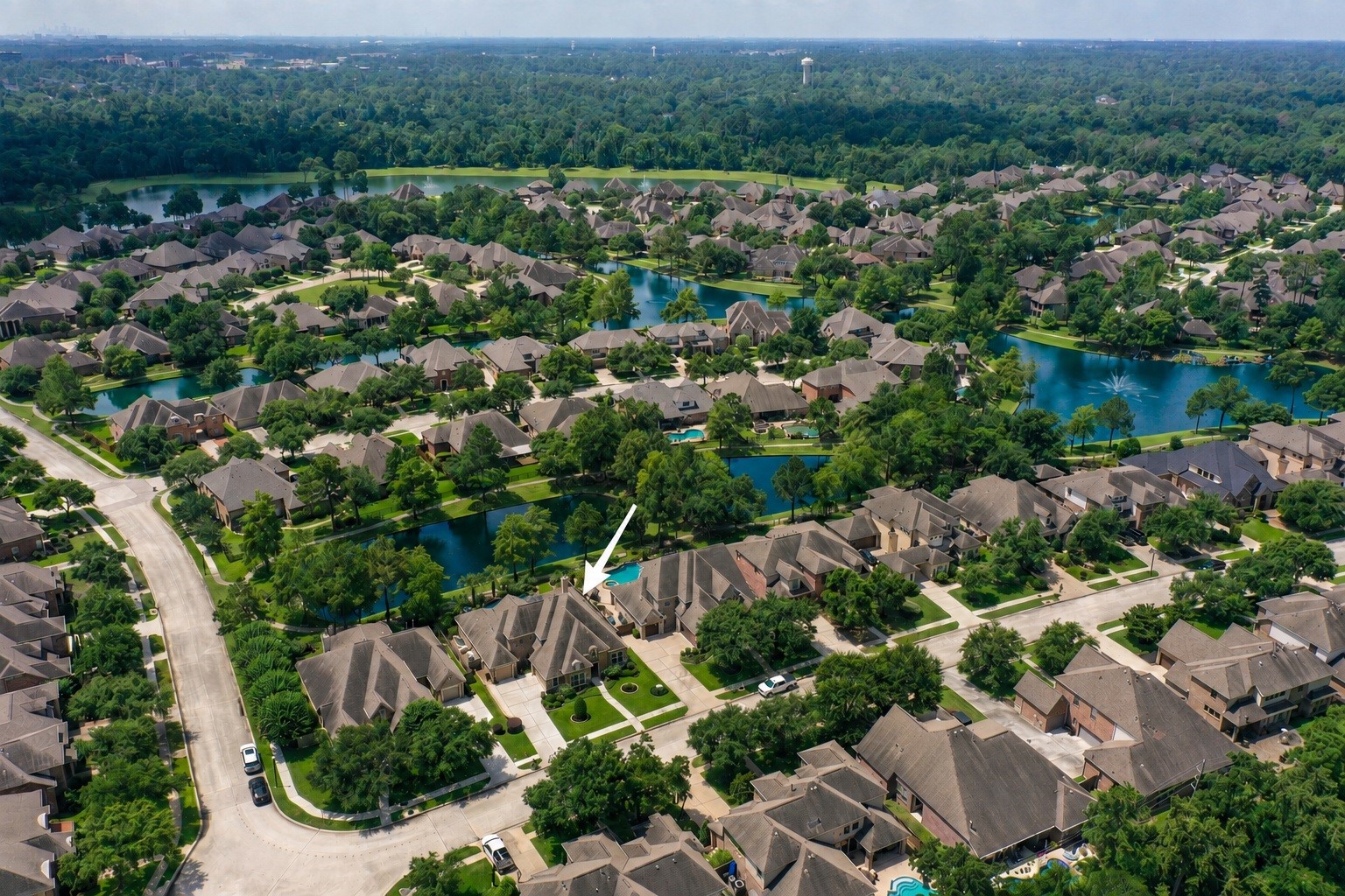 Marked from above, 2407 Hendricks Lakes Drive sits within the gated Lakes of Cypress Forest setting, surrounded by water, winding paths, fountains, and established greenery. This view helps place the homes poolside backyard within the larger water-front lifestyle, where the backyard connects naturally to the trails and scenic community spaces just beyond.
