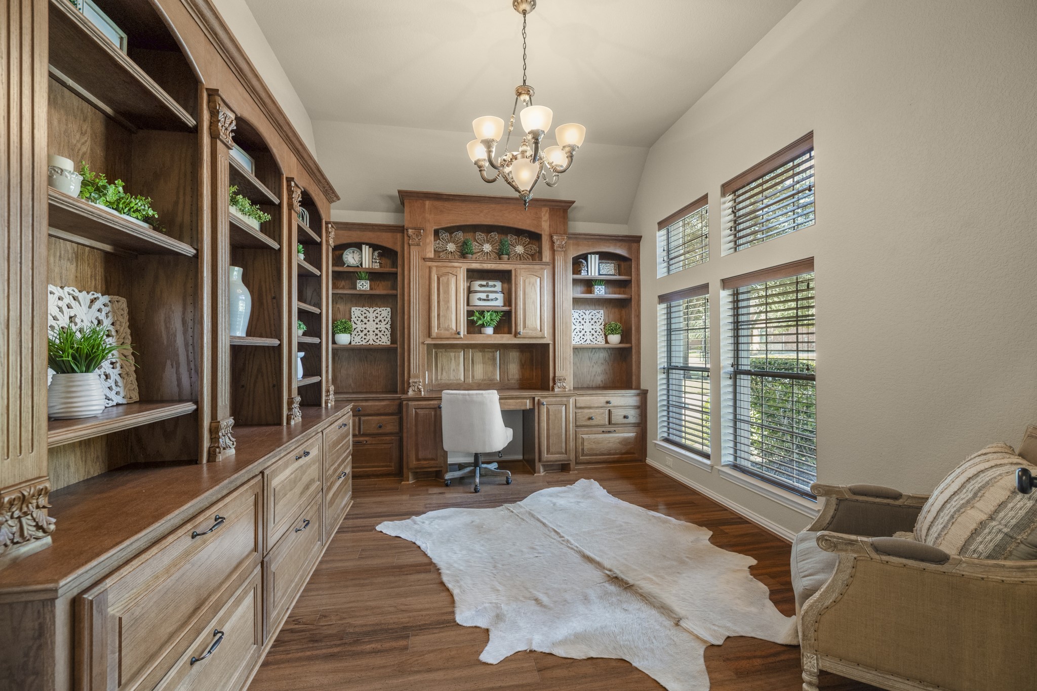 Working from home feels a little more inspired in this front study, where French doors, tall windows, and two walls of custom built-ins create a polished space just off the foyer. Rich wood cabinetry, detailed trim, file storage, display shelving, and lower cabinets give the room a library-like feel while keeping it practical for work, reading, or planning the day.
