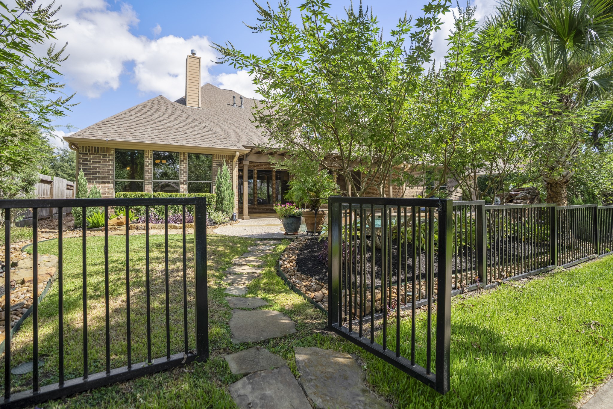 Stepping through the backyard gate, the homes water-front lifestyle continues onto the neighborhood trails just beyond the fence. The black wrought-iron fencing keeps the backyard visually connected to the lakeside setting, so the pool, covered pergola, and outdoor living spaces feel tied to the paths, water, and greenery that make Lakes of Cypress Forest so memorable.