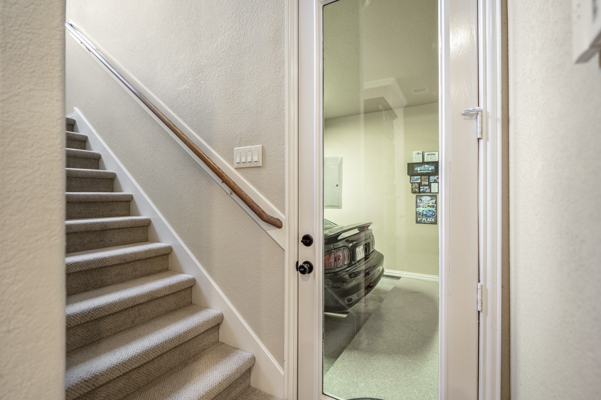 Just off the side of the kitchen, this hallway gives buyers a helpful look at how the homes upstairs spaces and garage layout connect. The stairs lead up to the game room, media room, and half bath, while the nearby access to the separate third garage bay shows how the home offers 3-car garage space while keeping that single bay distinct from the main 2-car garage.
