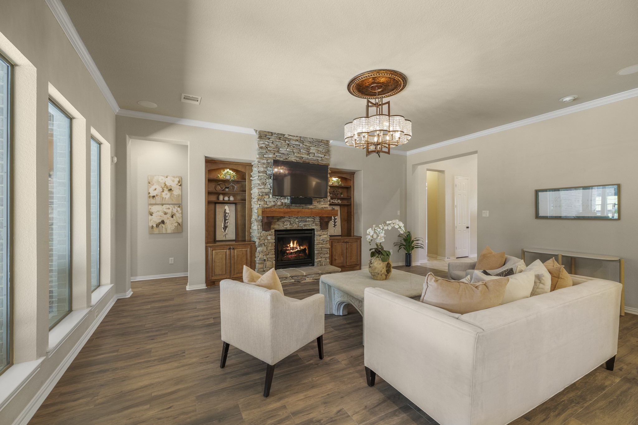 From the living room, the homes main gathering spaces feel connected without losing their sense of warmth, with the kitchen open on the right and the stone fireplace framed by custom lighted built-ins ahead. Rear windows keep the poolside setting close, tying this room back to the covered patio, spa, and water-front backdrop before the walkthrough continues into the primary suite.