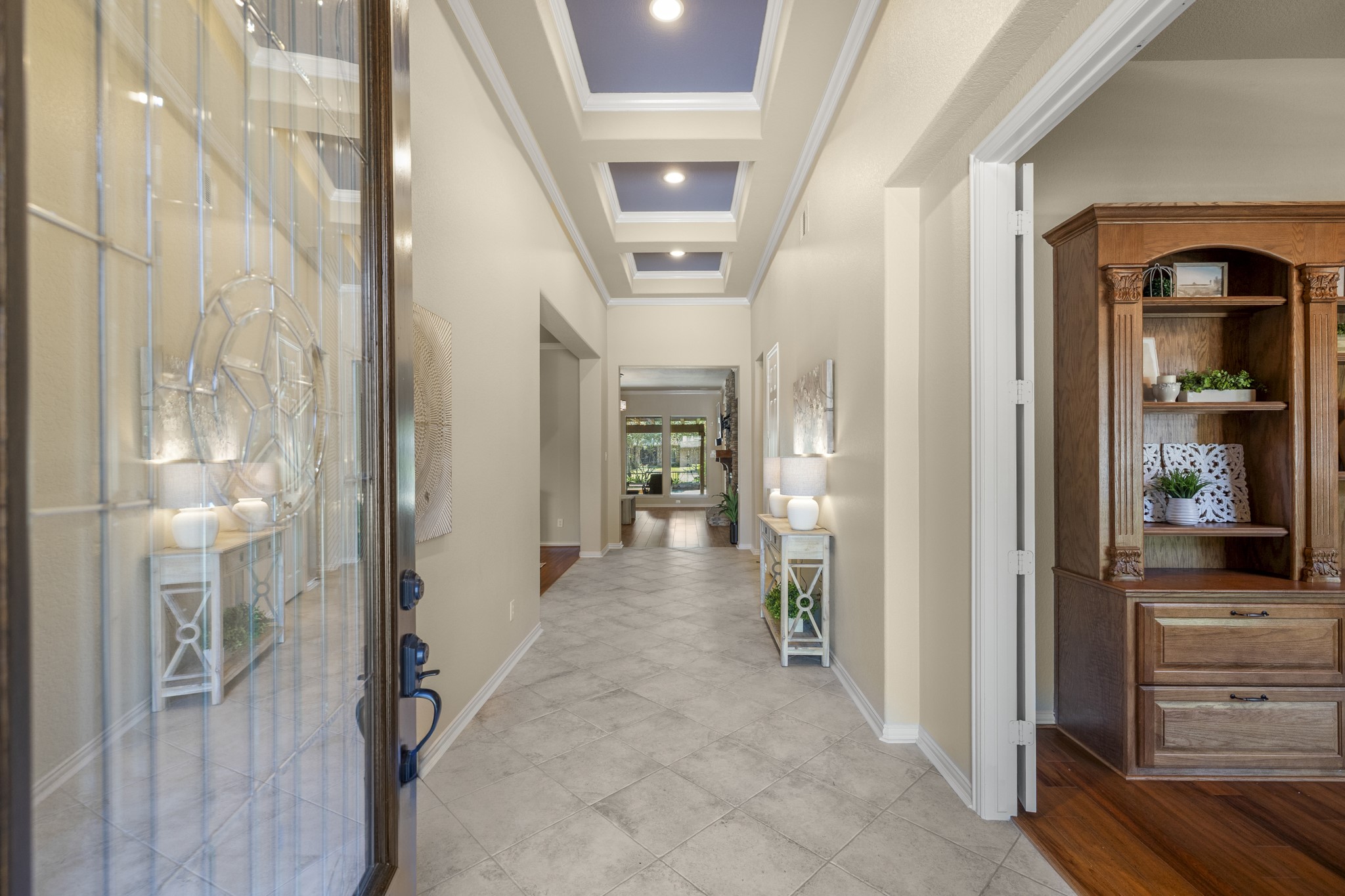 Stepping inside, the foyer introduces the homes tailored feel with high ceilings and French doors opening to the office/study on the right. The path continues forward toward the main living areas, giving the first few steps inside a clear sense of flow before the home opens toward the kitchen, living room, and water-view backyard beyond.
