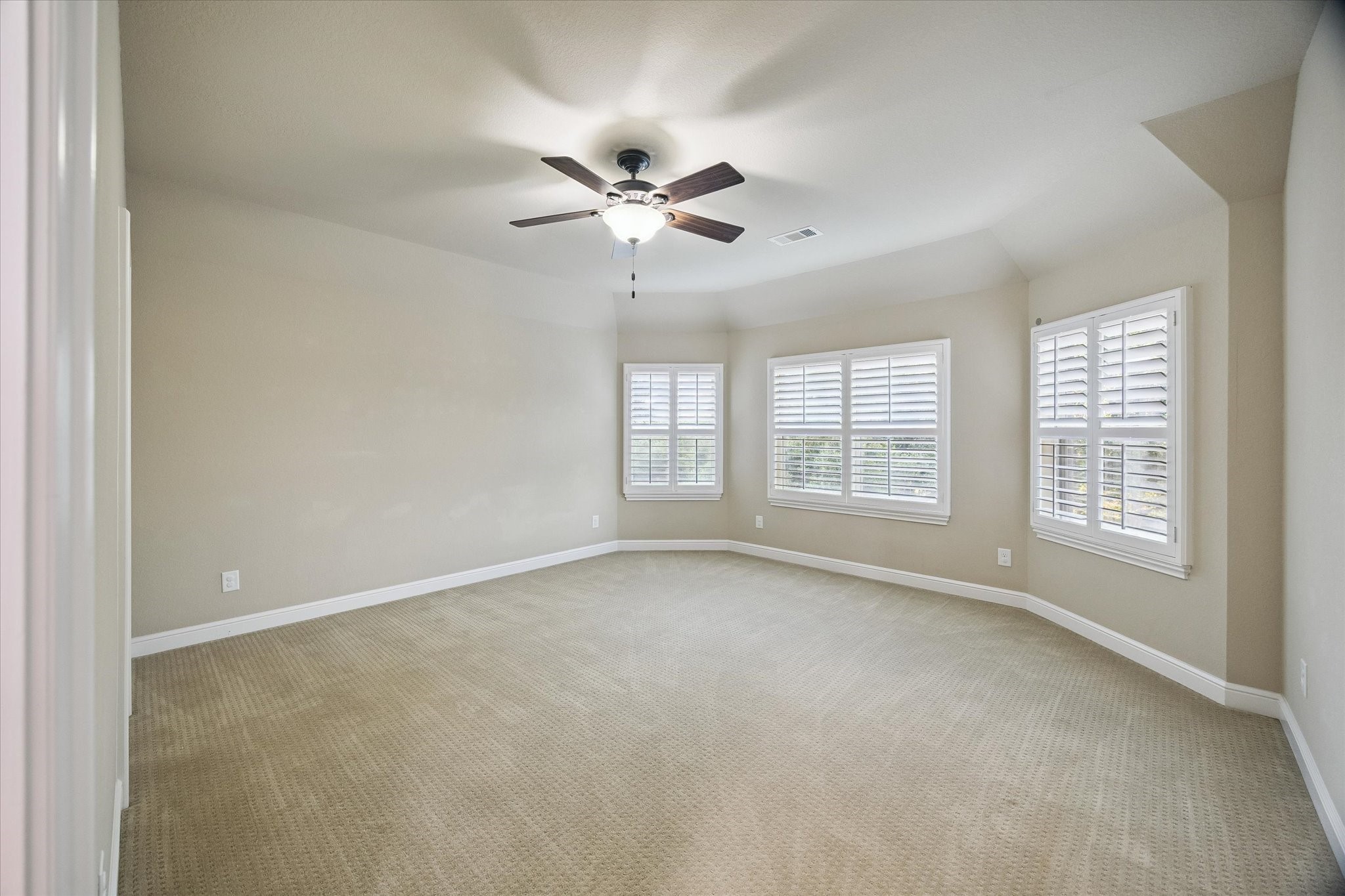 This generously sized secondary bedroom showcases elegant plantation shutters, abundant natural light, and a comfortable layout. A bright and welcoming space that can easily accommodate family, guests, or a personalized retreat.