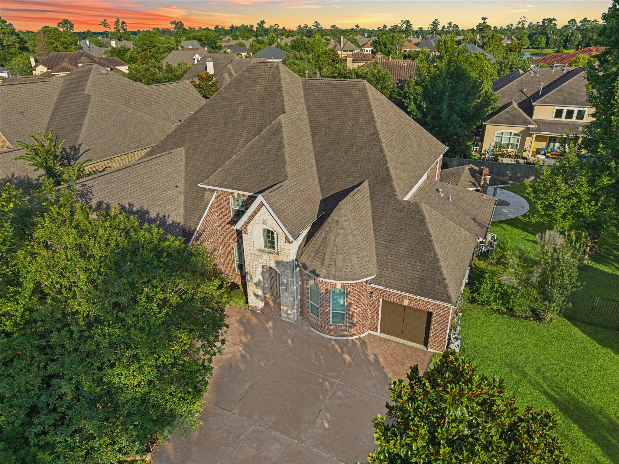 Aerial view showcasing the impressive curb appeal of this distinguished residence, featuring a spacious driveway, stately architecture, mature landscaping, and a beautifully positioned homesite within one of The Woodlands most sought-after communities.