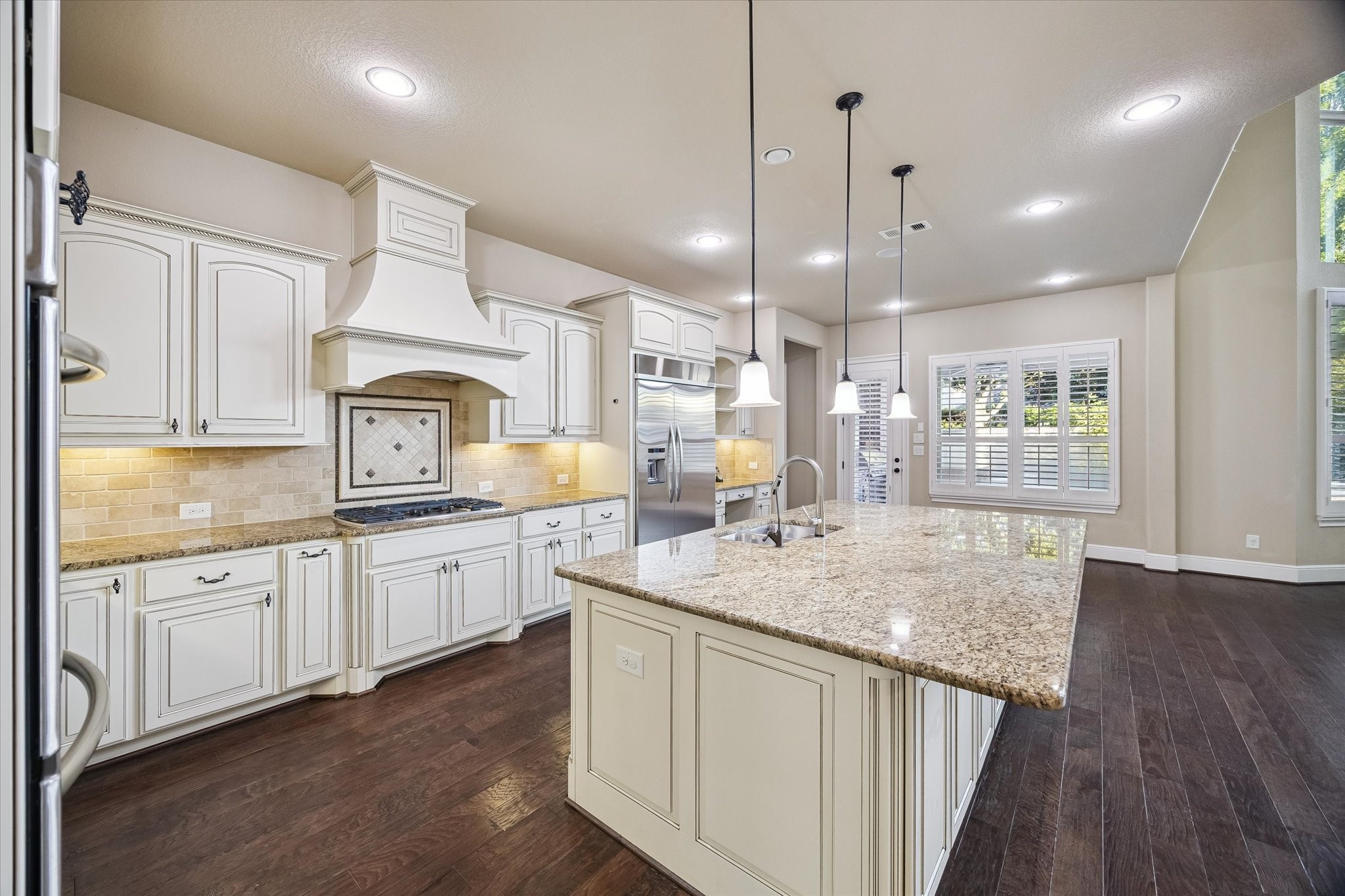 Designed for both everyday living and entertaining, the kitchen features an oversized island with seating, extensive cabinetry, abundant workspace, and a light-filled breakfast area. A thoughtfully designed built-in workstation offers a convenient space for meal planning, studying, or working from home while remaining at the center of the home's activity.
