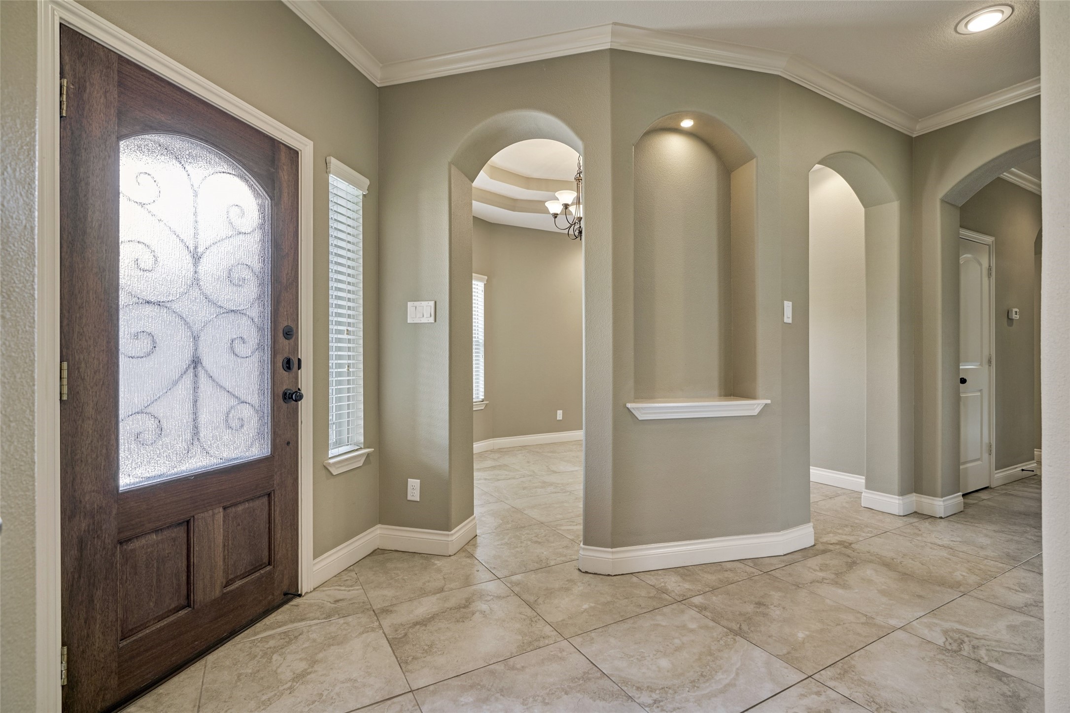 This side of the foyer has an art niche ready for a beautiful centerpiece. Enter into the formal dining room through either side of the arches.