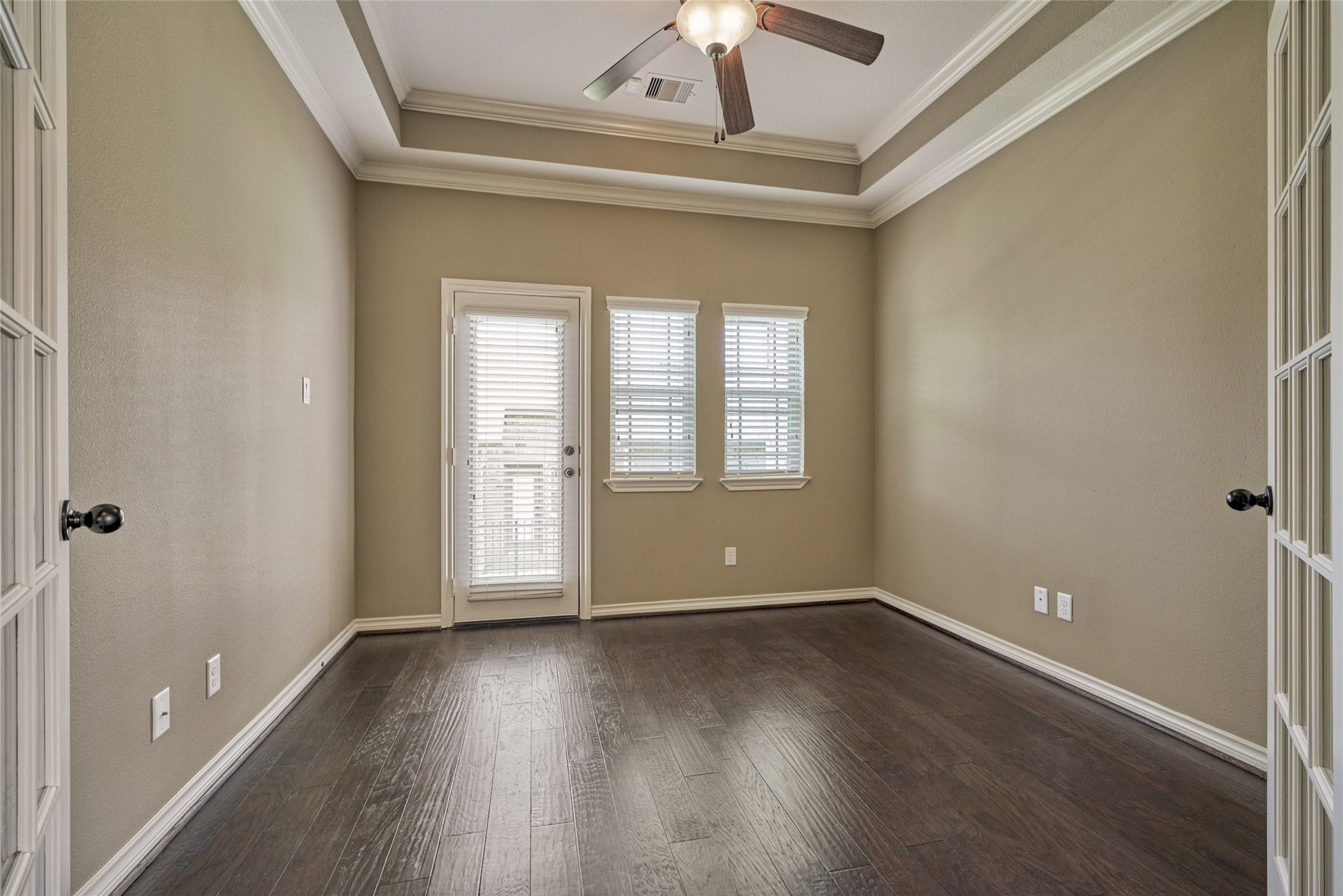 Another view of the study with trey ceiling and rich wood flooring. The exterior door gives access to the side yard.