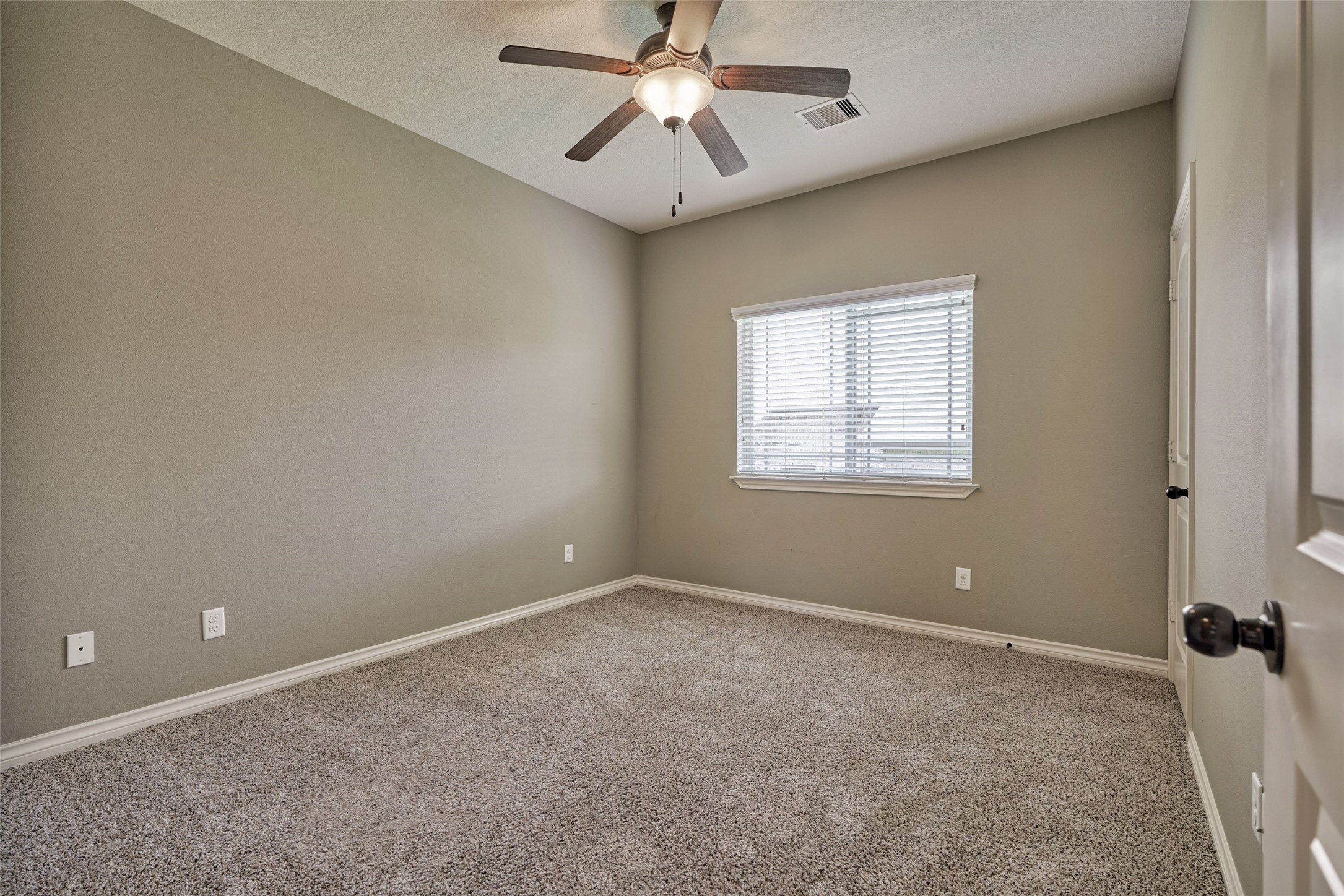 This is one of the two secondary bedrooms with ceiling fan and plush carpeting.