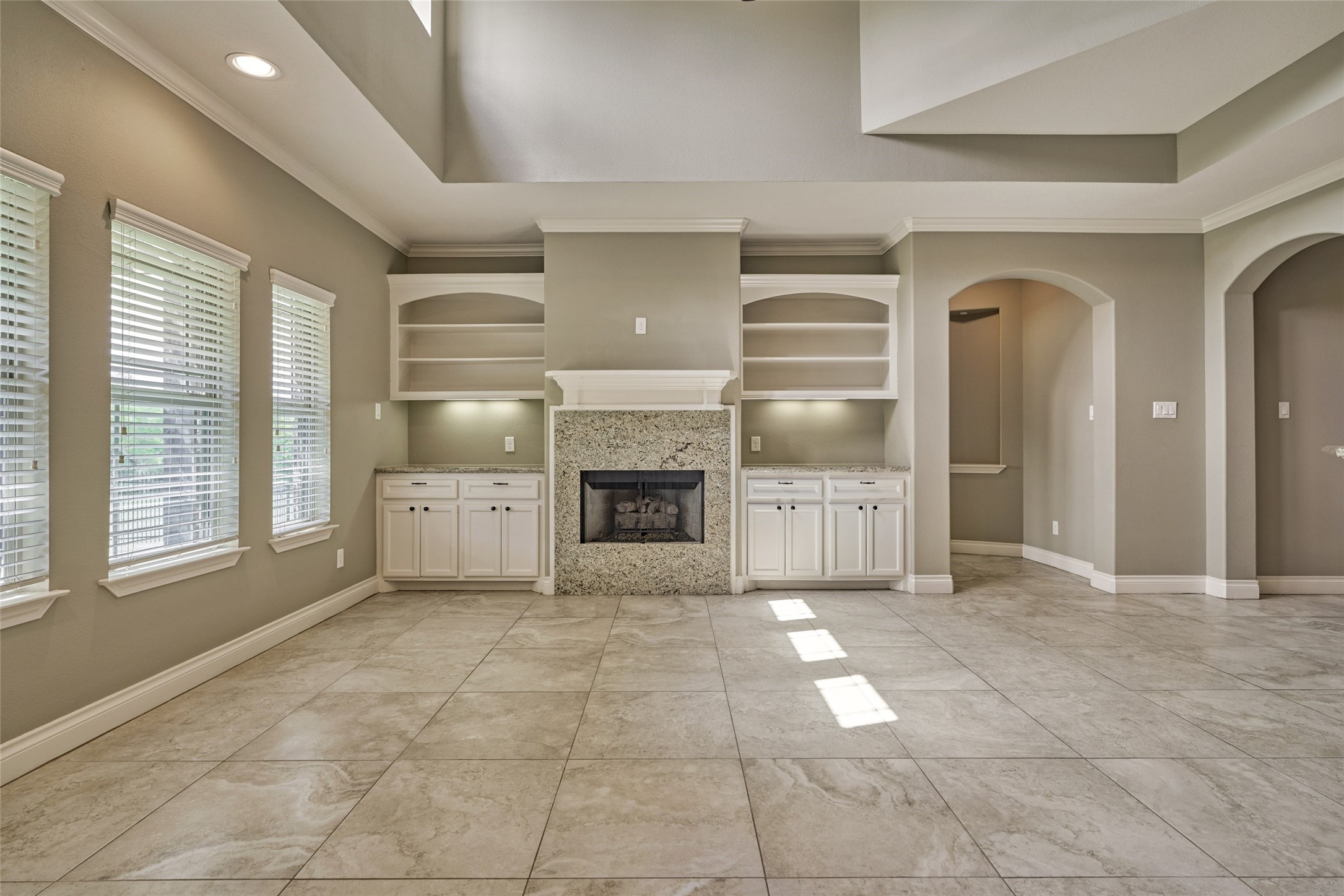 The arch to the right of the entertainment center leads to the spacious primary bedroom.