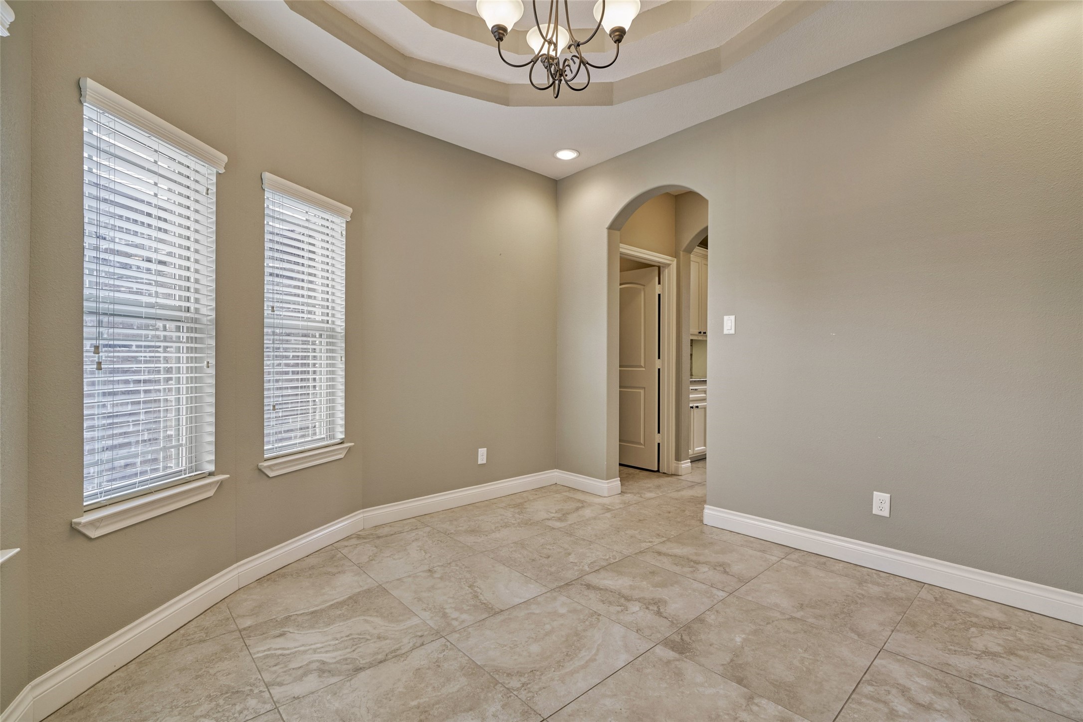 Dining room with trey ceiling has a wall full of windows for lots of natural light.