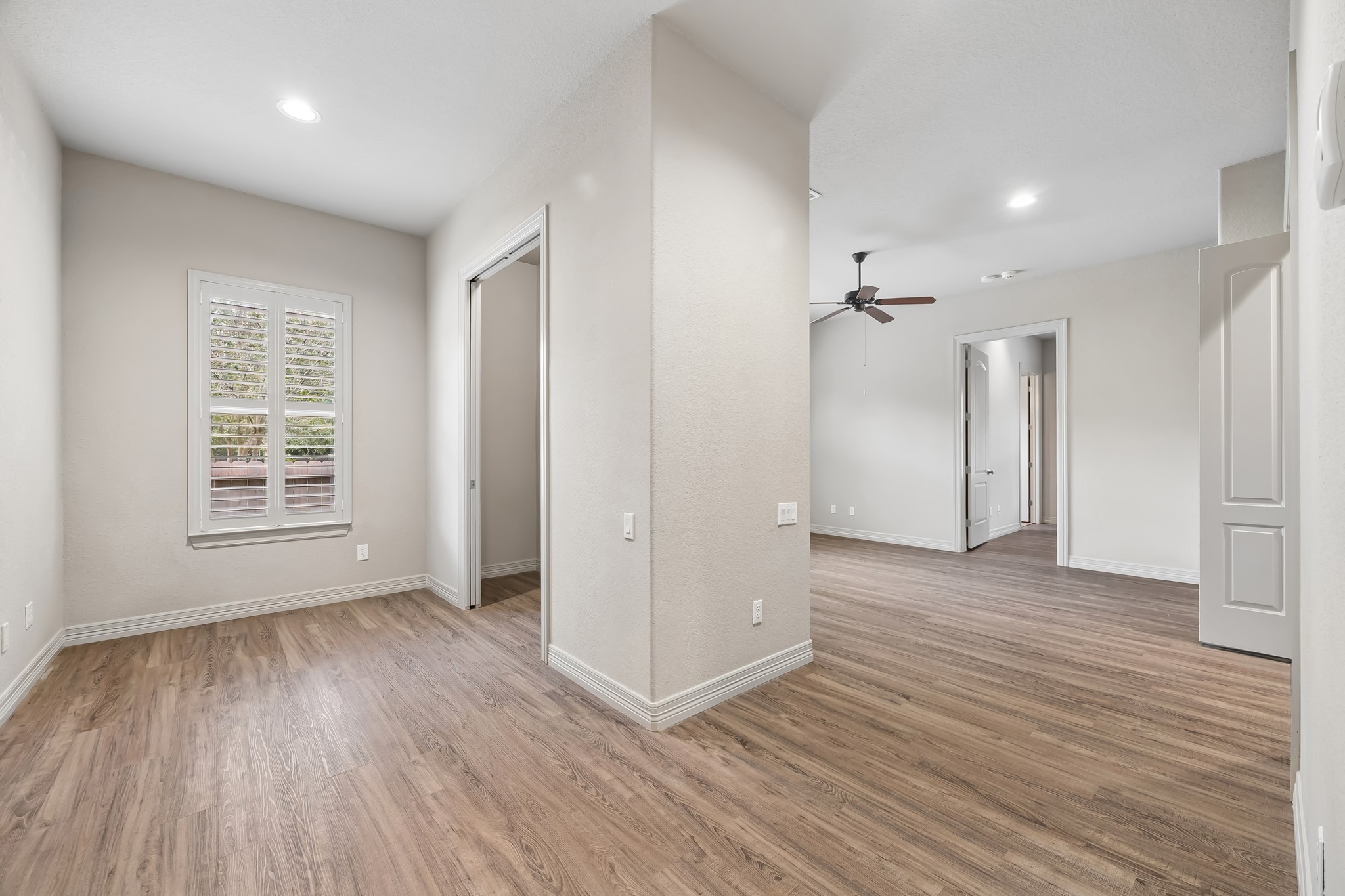 Bright and inviting space featuring beautiful wood flooring, neutral walls, and recessed lighting, offering a versatile layout with a windowed nook and a ceiling fan for comfort. This suite includes a living area, bedroom with ample storage and kitchenette for those long term visitors.