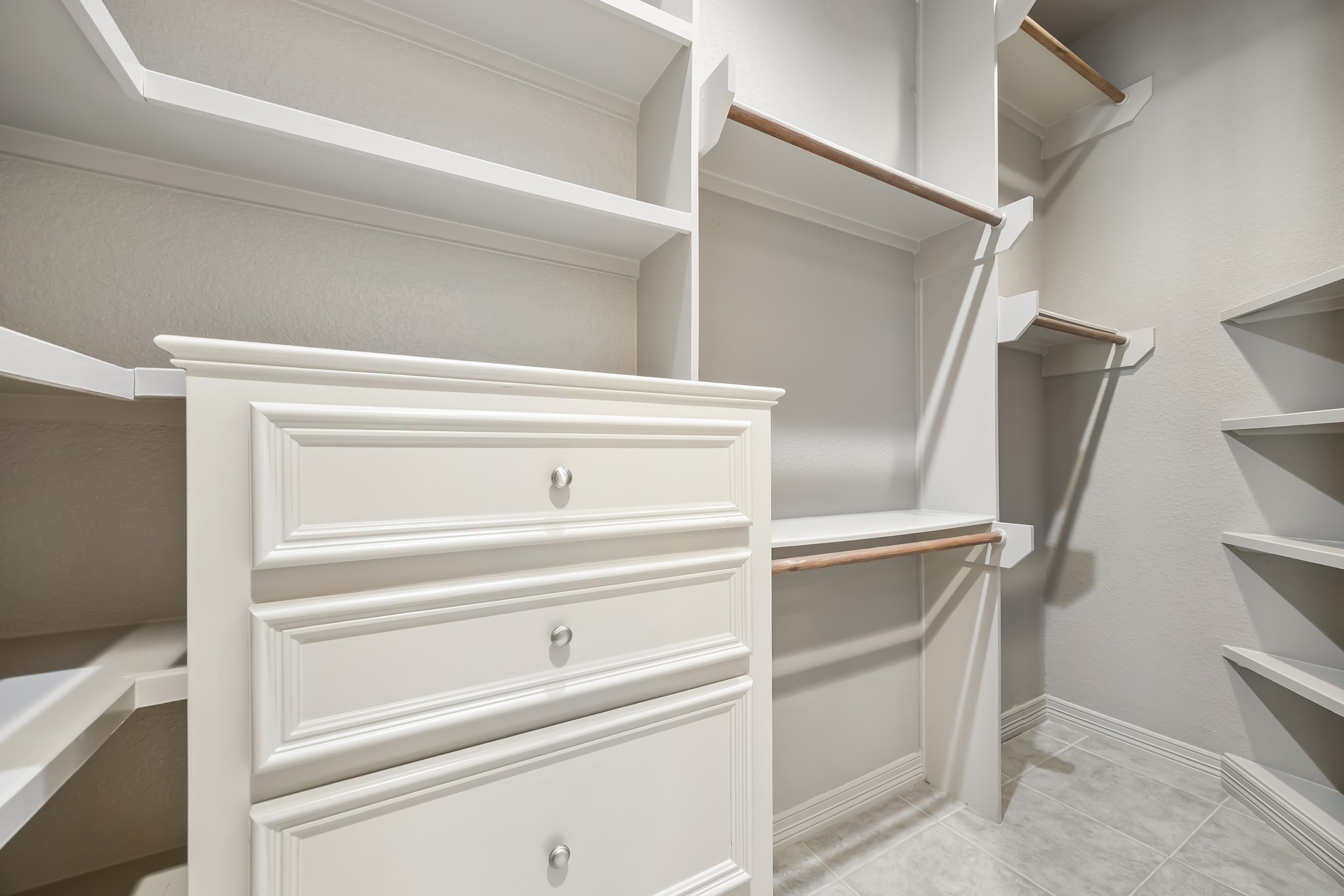 Spacious walk-in closet featuring built-in shelving, ample hanging space, and elegant cabinetry for organized storage.