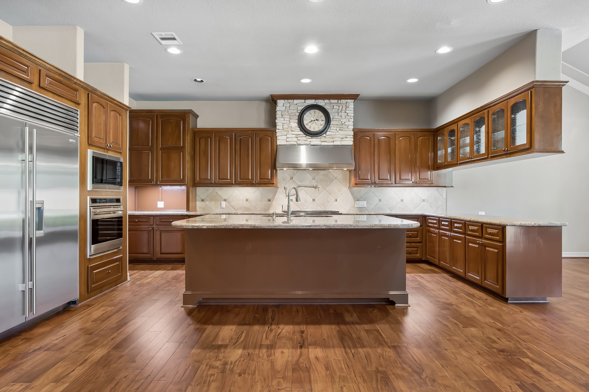 Spacious kitchen with rich wooden cabinetry, sleek stainless steel appliances, and a large central island perfect for gathering.