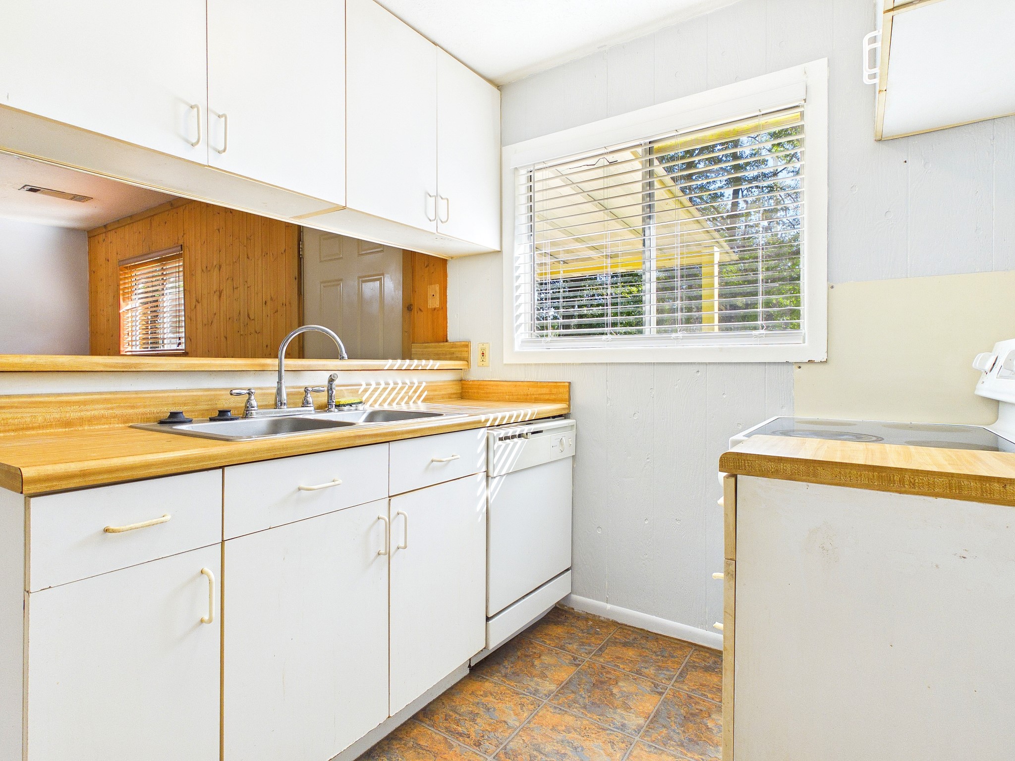 Charming kitchen featuring bright natural light, ample cabinetry, and a cozy open layout with a functional double sink and dishwasher.