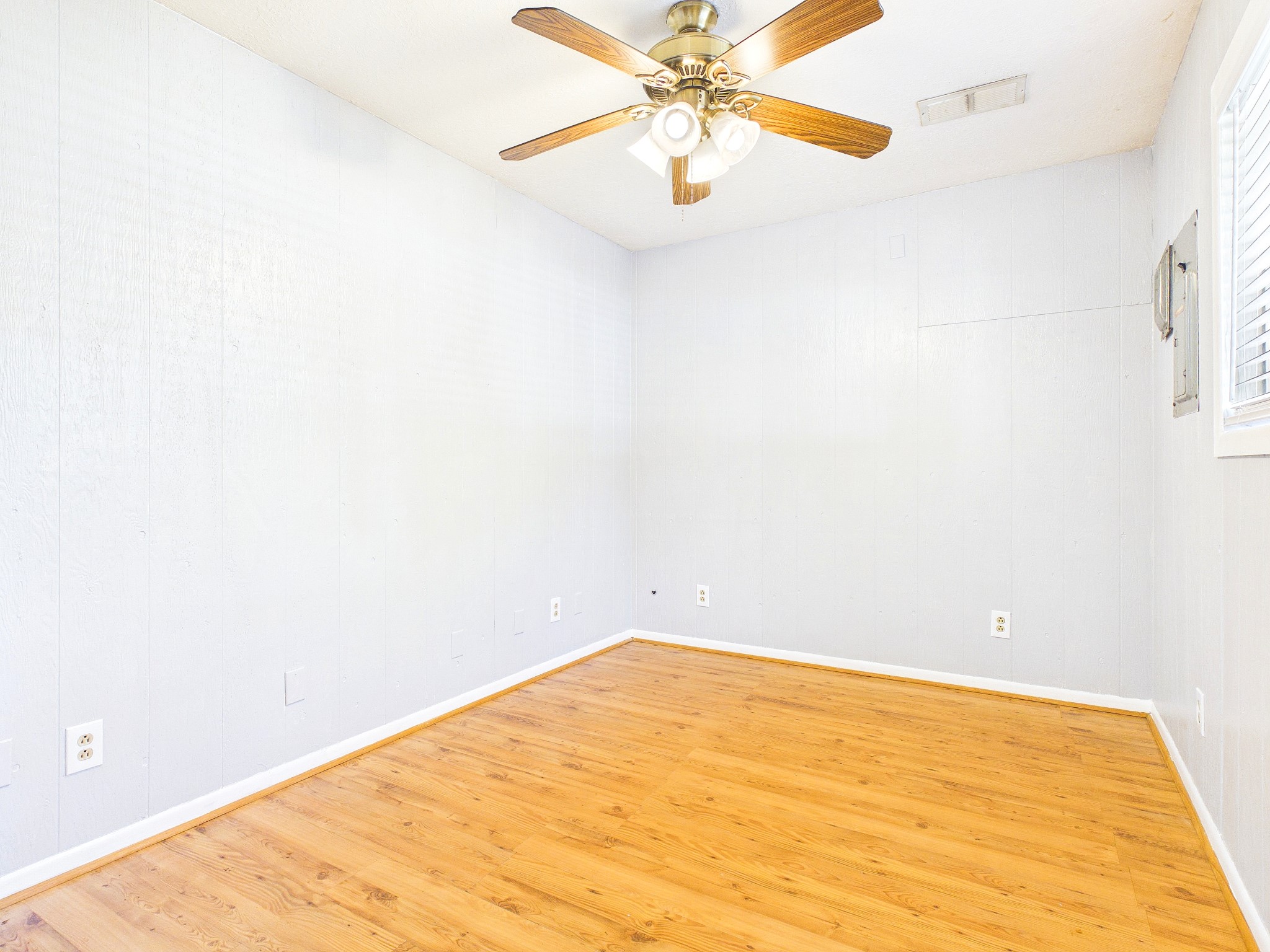 Bright and inviting room with warm floors and a classic ceiling fan, perfect for a cozy retreat or versatile living space.