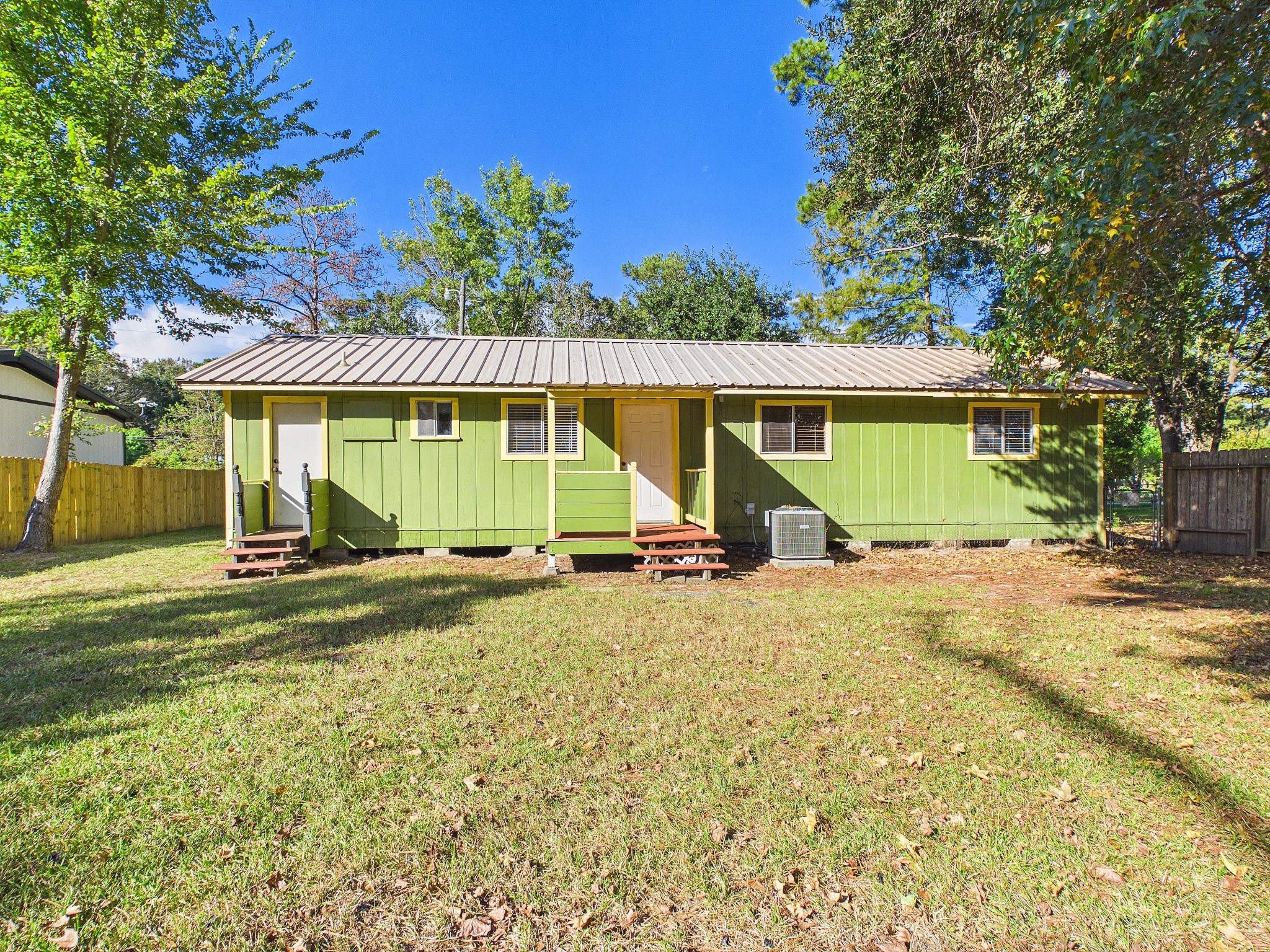 Charming home with a metal roof, set on a spacious grassy lot, surrounded by mature trees for added privacy.