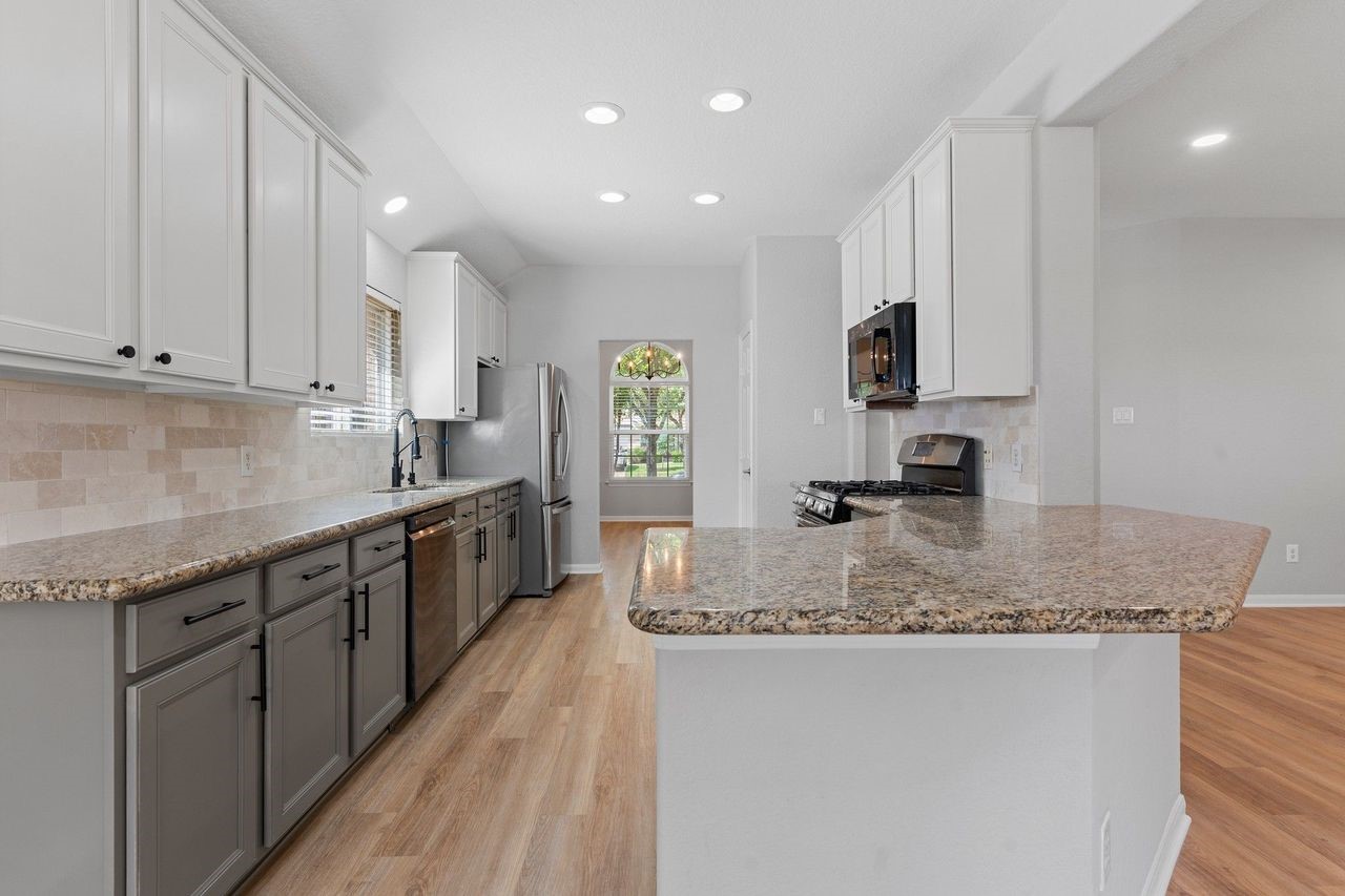 The gourmet kitchen features beautiful tall custom white shaker cabinets, a designer tile backsplash, and custom-painted lower cabinets that add a stylish, modern touch. With direct access to the formal dining room, serving family meals and entertaining guests is both easy and convenient.