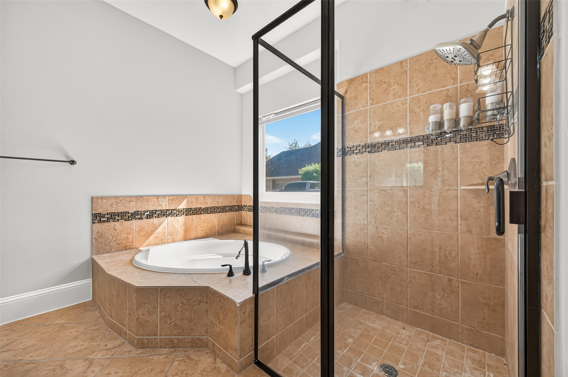Spa-like primary bath! Indulge in the deep corner soaking tub with elegant tile detailing. Features a massive granite-topped vanity with dual sinks, rich wood cabinetry, a large framed mirror, stylish lighting, and a massive walk-in layout.