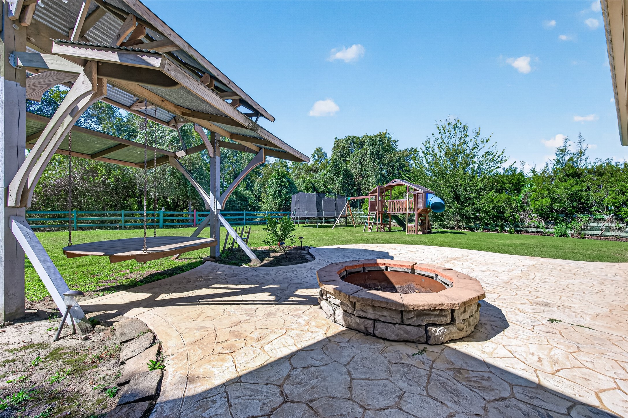 backyard oasis! Massive covered patio with stone pillars, stamped concrete extension, built-in fire pit, and plenty of green space to entertain.