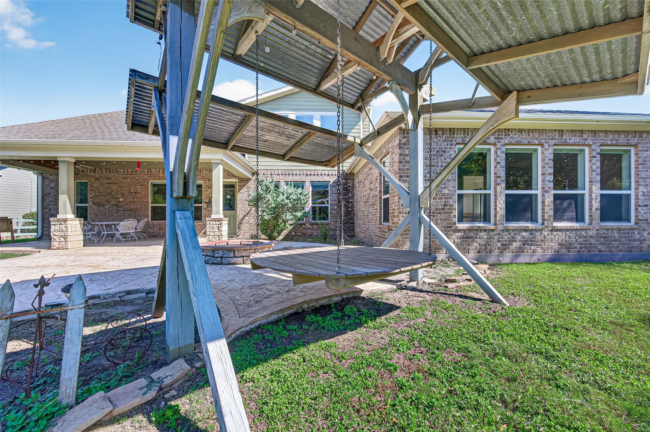 backyard oasis! Massive covered patio with stone pillars, stamped concrete extension, built-in fire pit, and plenty of green space to entertain.