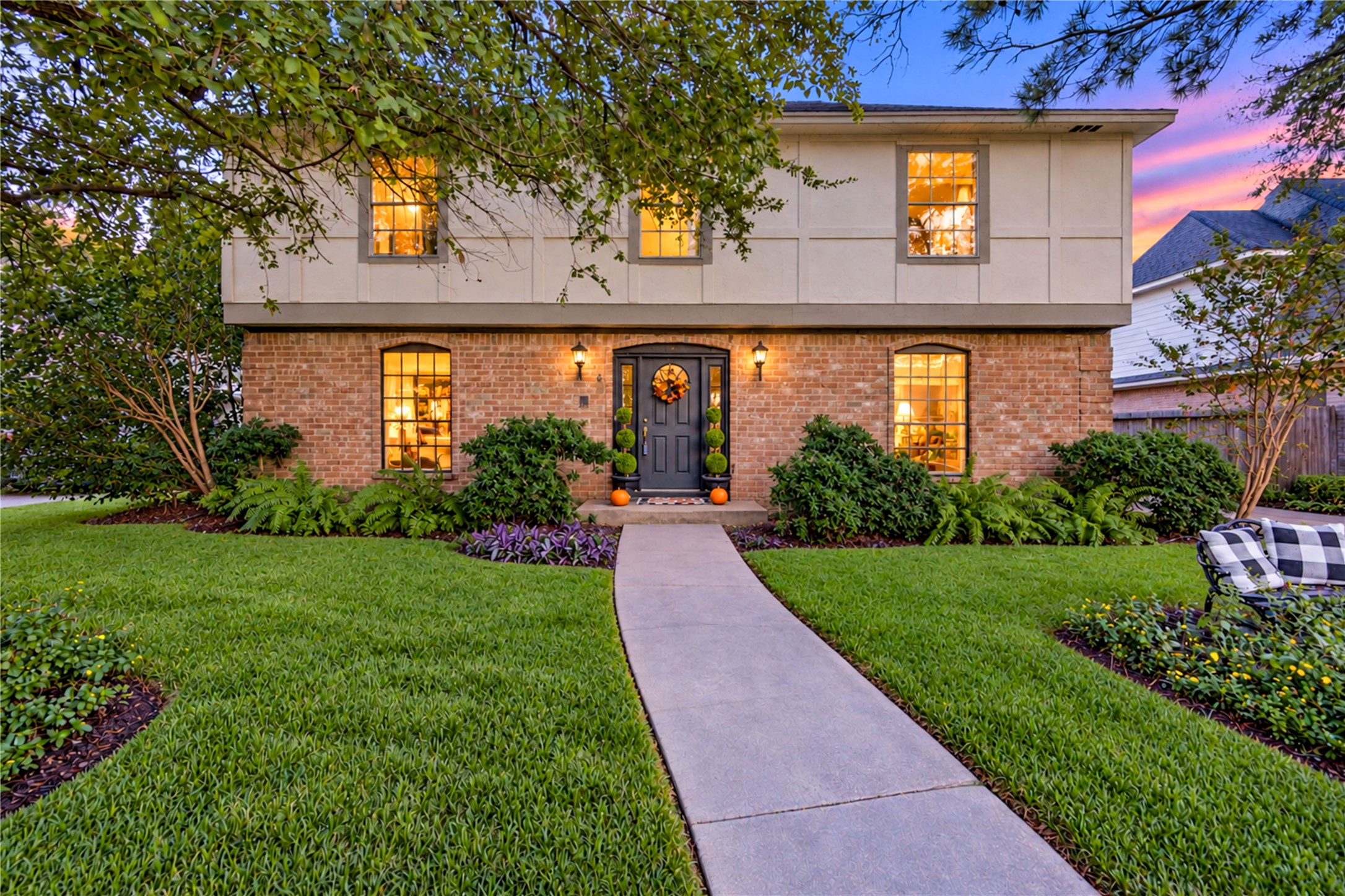 A warm welcome awaits as the sun begins to set! This beautiful two-story home shines with timeless brick architecture, lush landscaping and mature shade trees. The softly illuminated front entry and inviting walkway create a picture-perfect setting, while the peaceful evening glow adds a touch of magic. Imagine returning home after a busy day to this charming retreat in the heart of Village West, where classic curb appeal meets everyday comfort!
