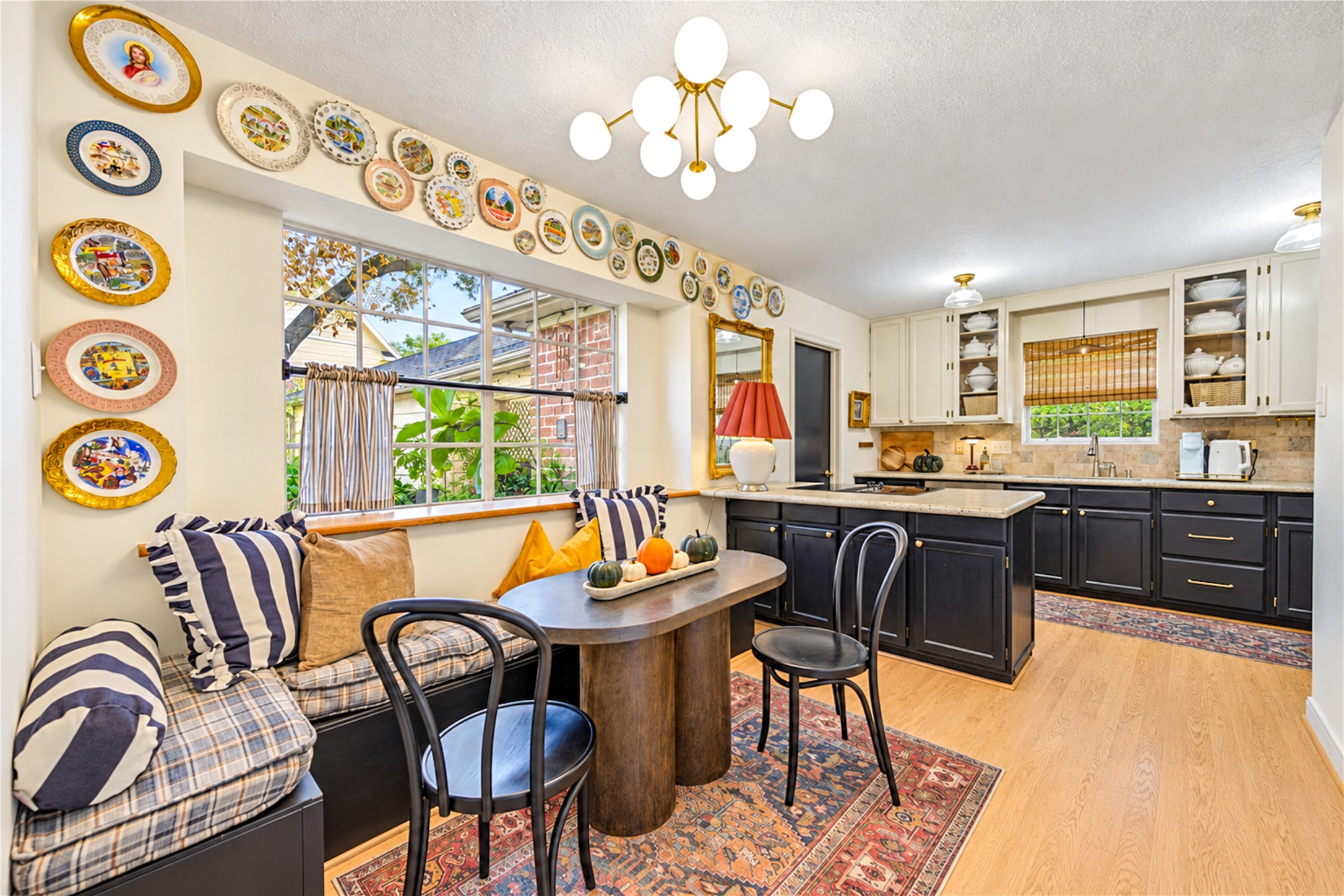 A charming breakfast nook that makes everyday dining feel special! The cozy built-in window seat overlooks lush greenery, creating the perfect spot for morning coffee or leisurely weekend breakfasts. A stylish statement chandelier and beautiful wood floors add warmth, while the seamless connection to the kitchen makes everything from casual meals to entertaining feel effortless. Designer personality shines in every detail!
