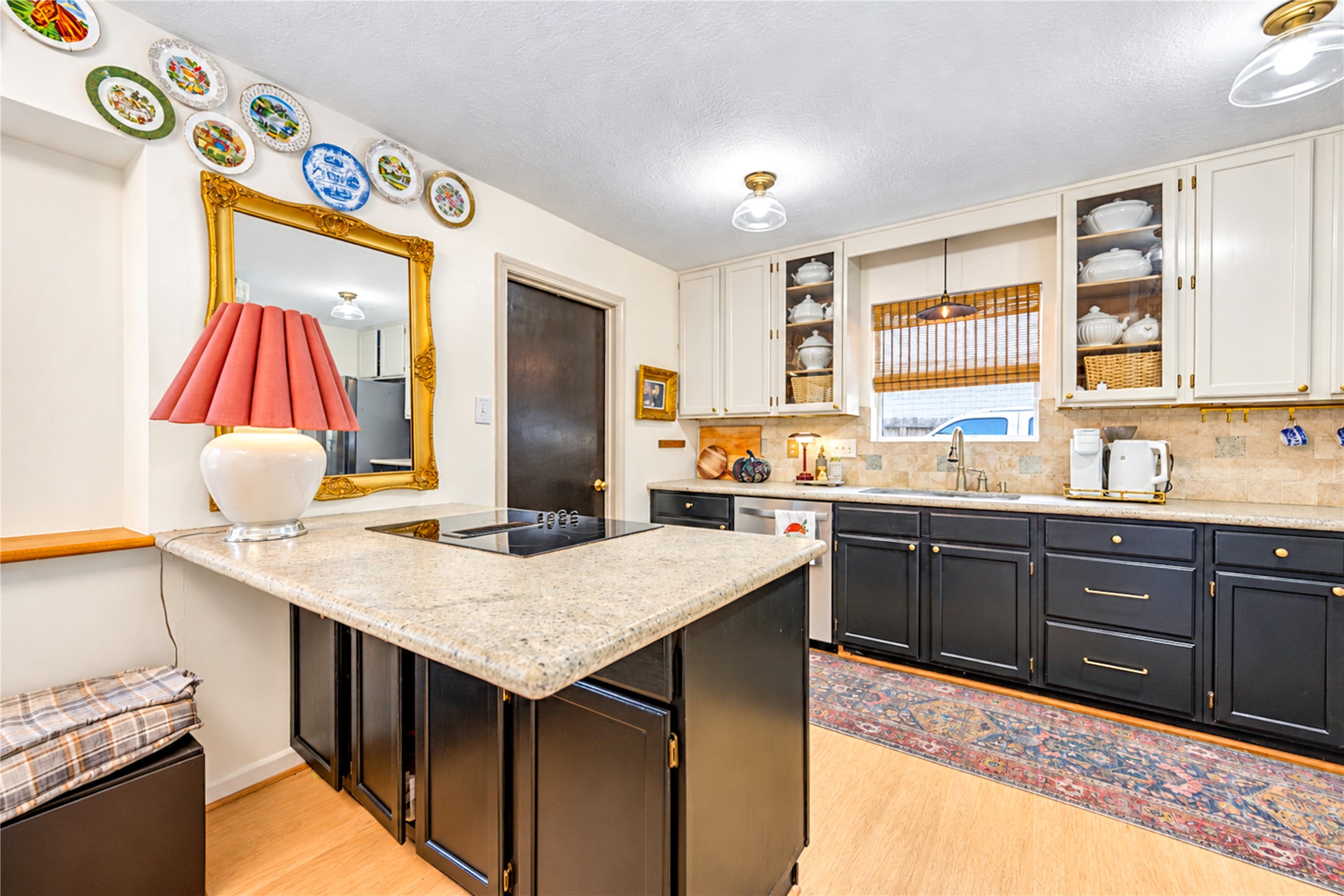 The perfect gathering spot! This inviting kitchen features a spacious granite-topped breakfast bar with a convenient cooktop, rich contrasting cabinetry and a beautiful travertine backsplash. Whether preparing a favorite meal, enjoying casual conversation over coffee or entertaining friends, this thoughtfully designed space brings warmth, character and everyday functionality to the heart of the home!