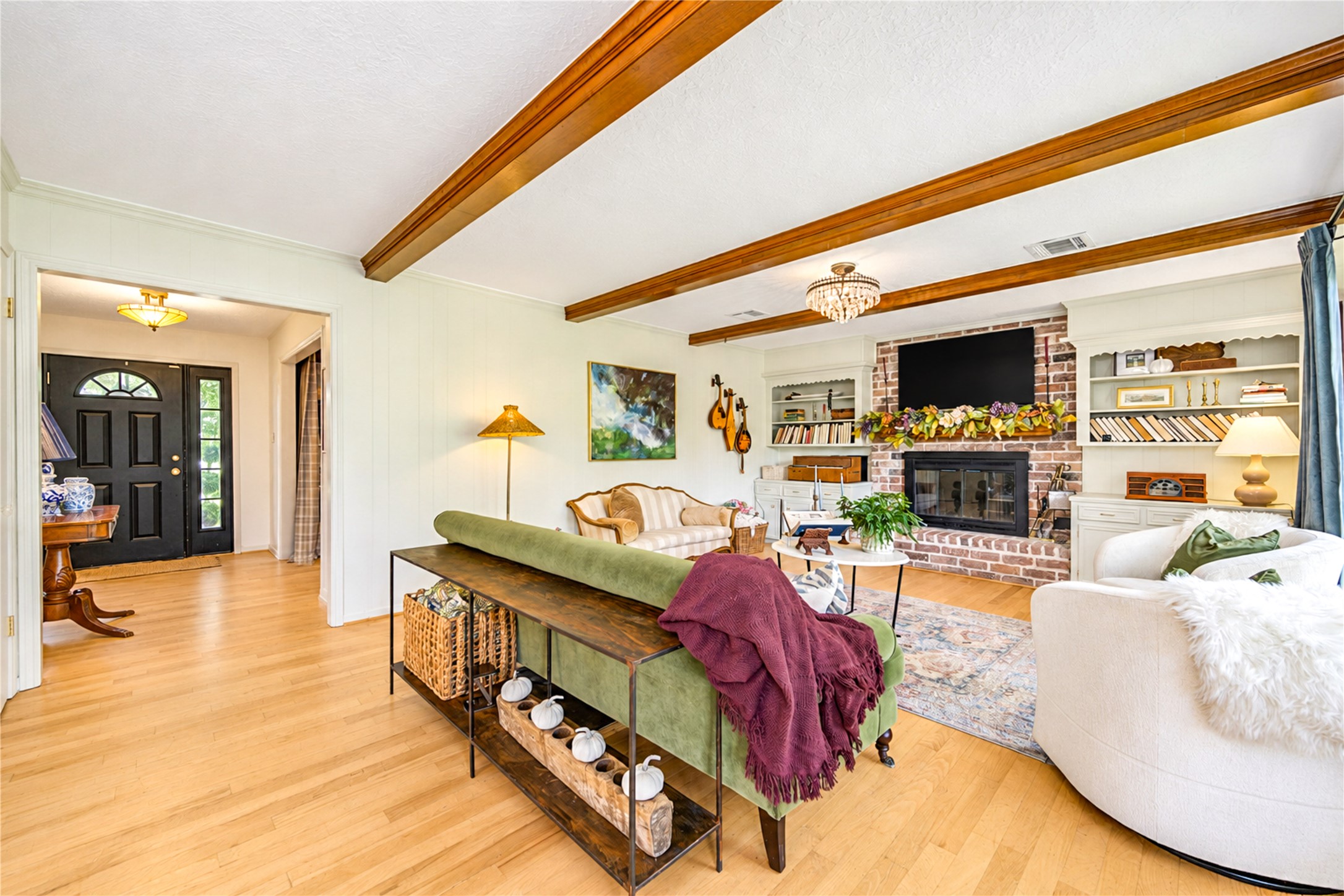A fresh perspective on comfortable living! From this inviting angle, the living room showcases its soaring ceilings, exposed wood beams and beautiful wood floors. Thoughtfully curated designer touches bring warmth and personality, while the open connection to the kitchen keeps everyone part of the conversation. Whether hosting friends or enjoying a relaxing evening at home, this space makes everyday moments feel special!