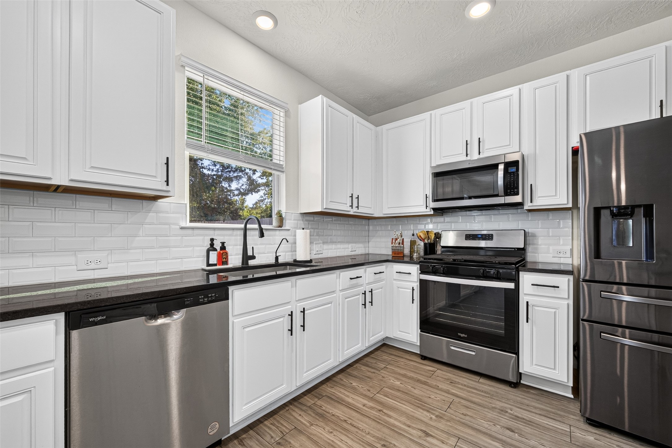 Natural light brightens this beautiful kitchen, highlighting the white cabinetry and stainless steel appliances. Imagine enjoying the convenience of a functional layout that makes everyday meal preparation effortless.