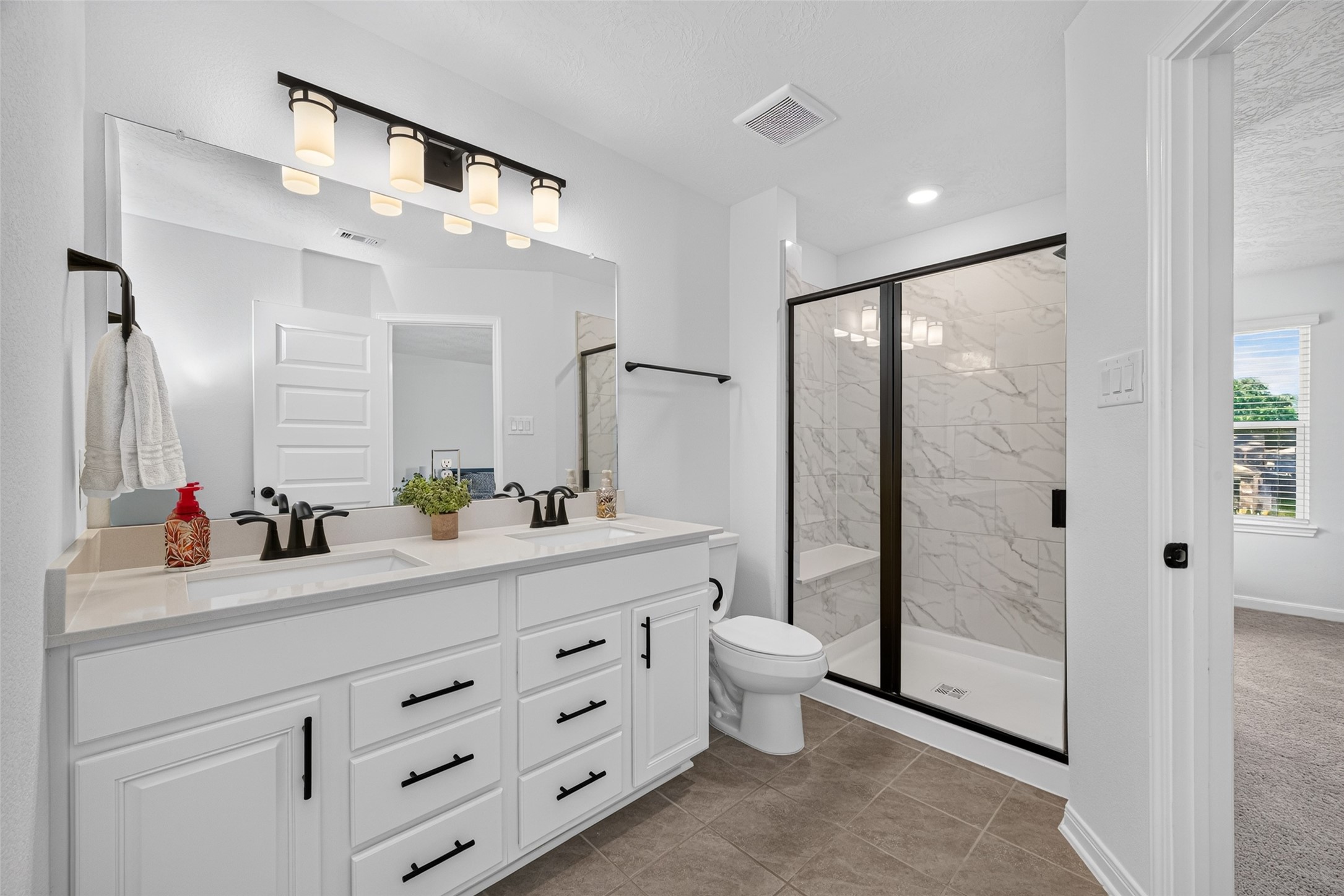 Enjoy the convenience of a private ensuite bathroom featuring an extended vanity and glass-enclosed shower. The spacious countertop and generous cabinetry make it easy to keep everyday essentials organized.