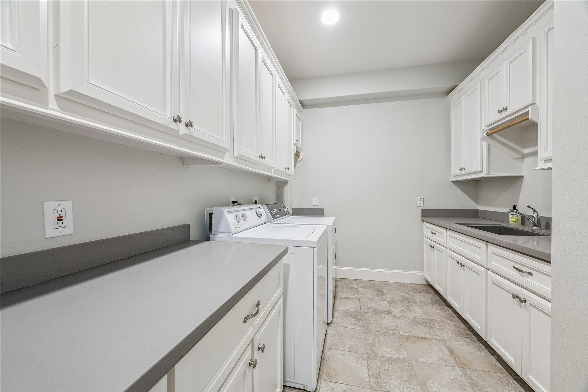 This laundry room has it all with tons of cabinetry, large undermount utility sink, hanging rod, folding counter and the washer and dryer are included