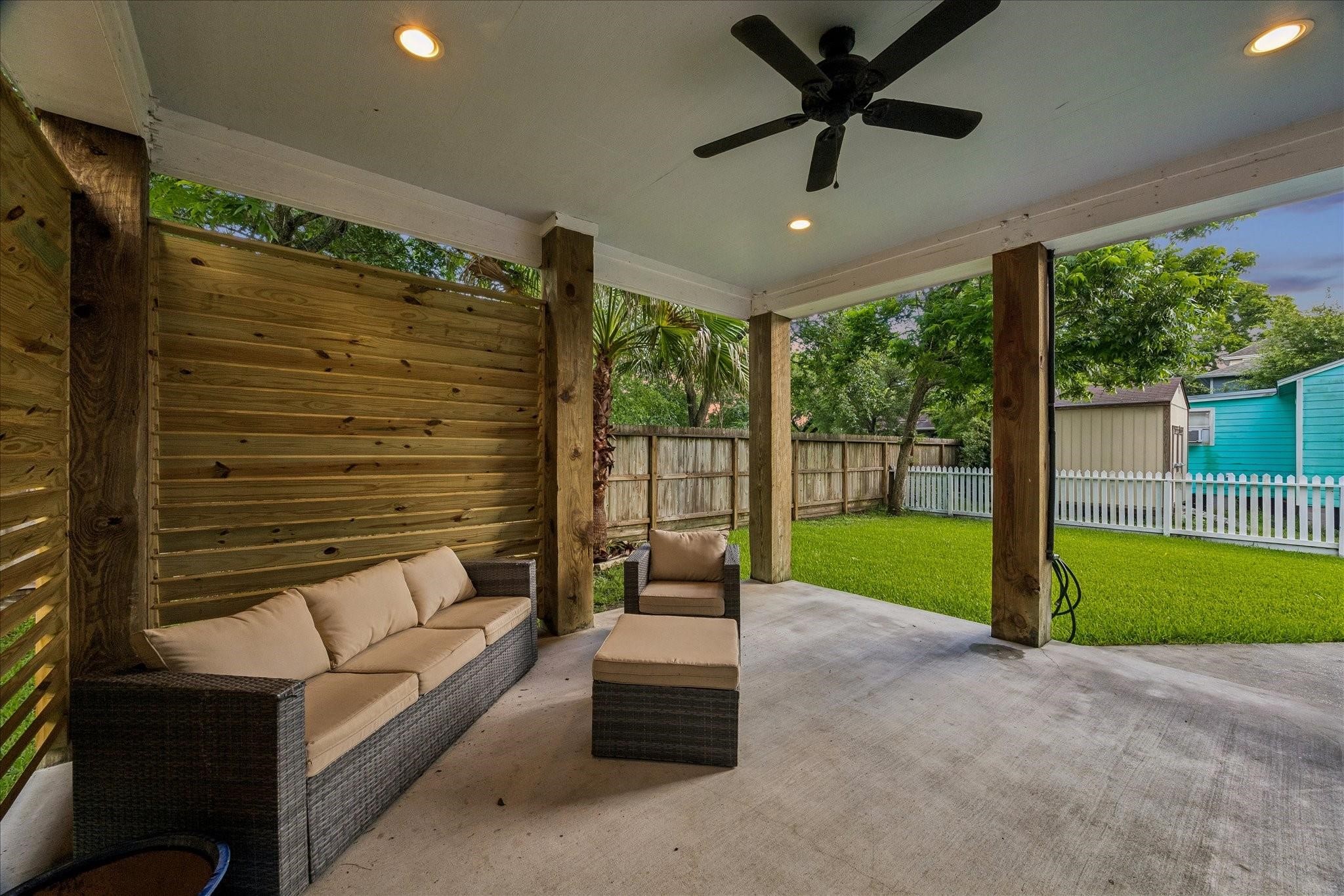 This backyard features a covered patio with ceiling fan, recessed lighting and louvered walls for added privacy