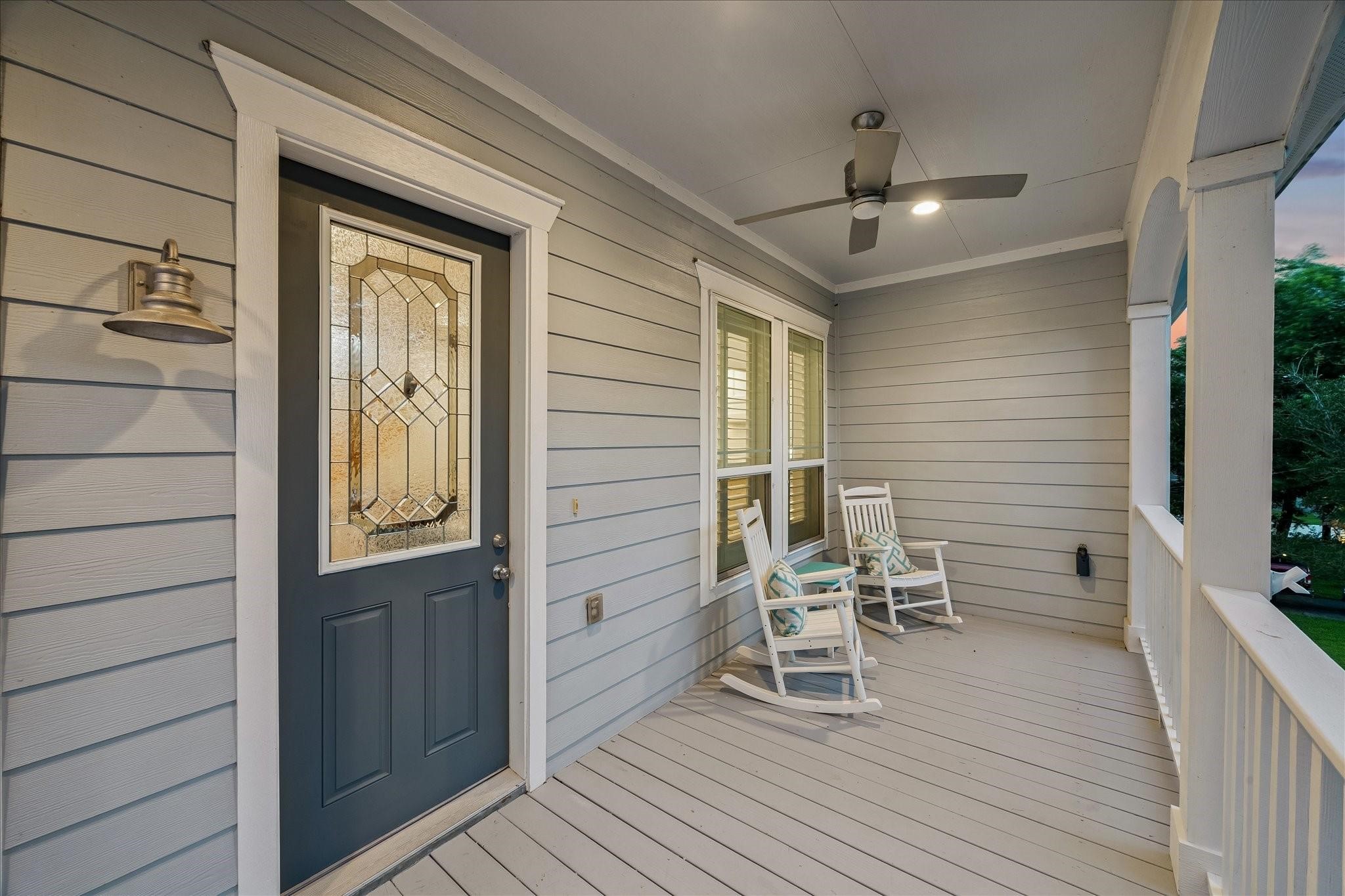 Relax on the covered front porch with a decorative glass front door and ceiling fan for comfort. Perfect for morning coffee or an evening cocktail Relax on the covered front porch with a decorative glass front door and ceiling fan for comfort. Perfect for morning coffee or an evening cocktail
