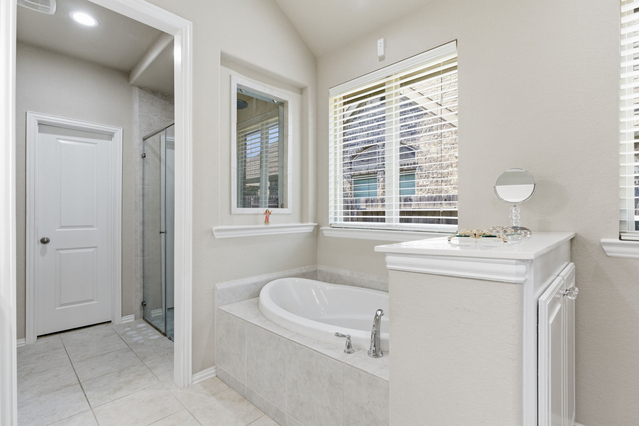 Separate jetted soaker tub for relaxation compliments the private walk-in shower.